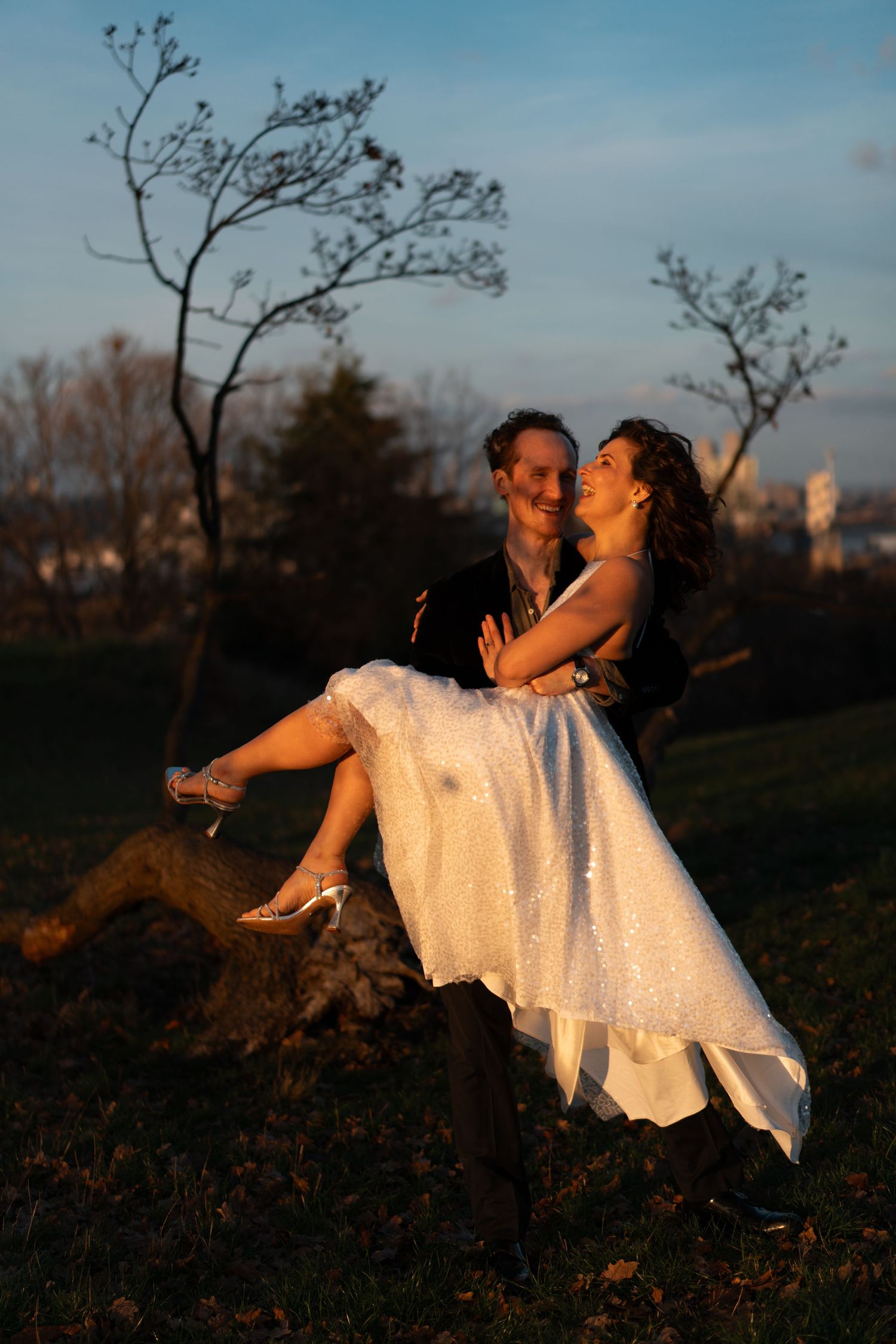 Two people share an intimate dance moment outdoors during sunset with white clothing.