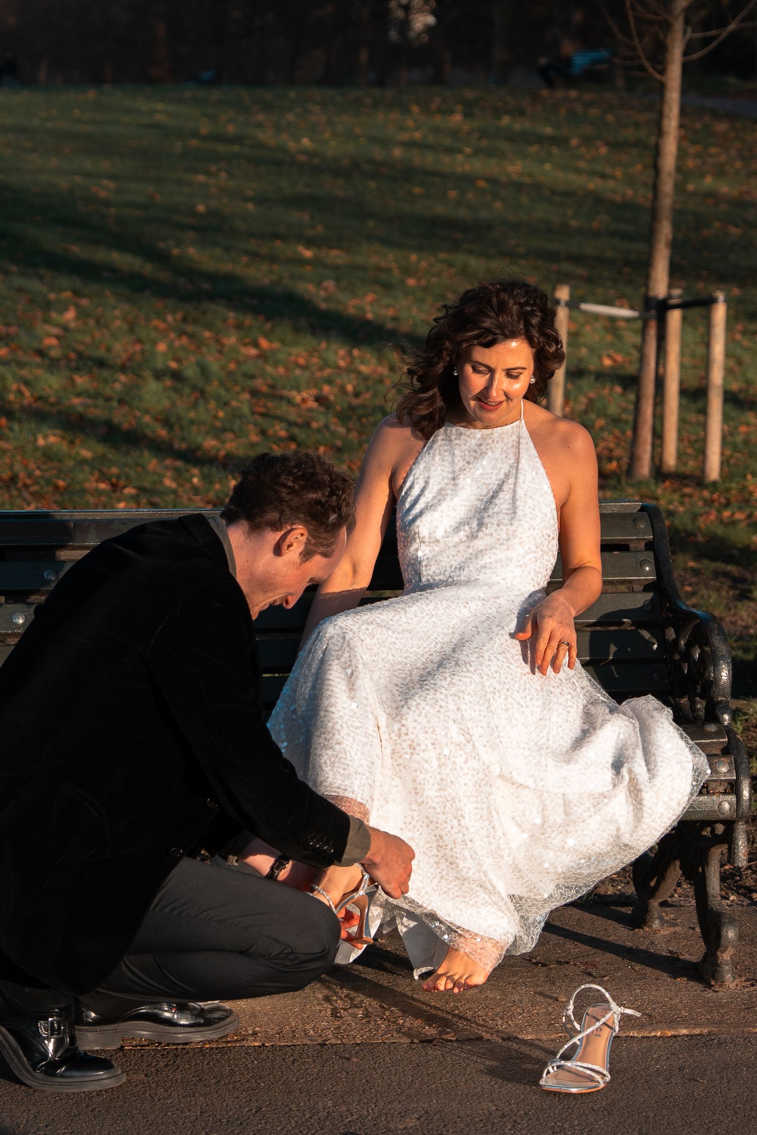 A photographer captures artistic angles of a white dress against a park backdrop.