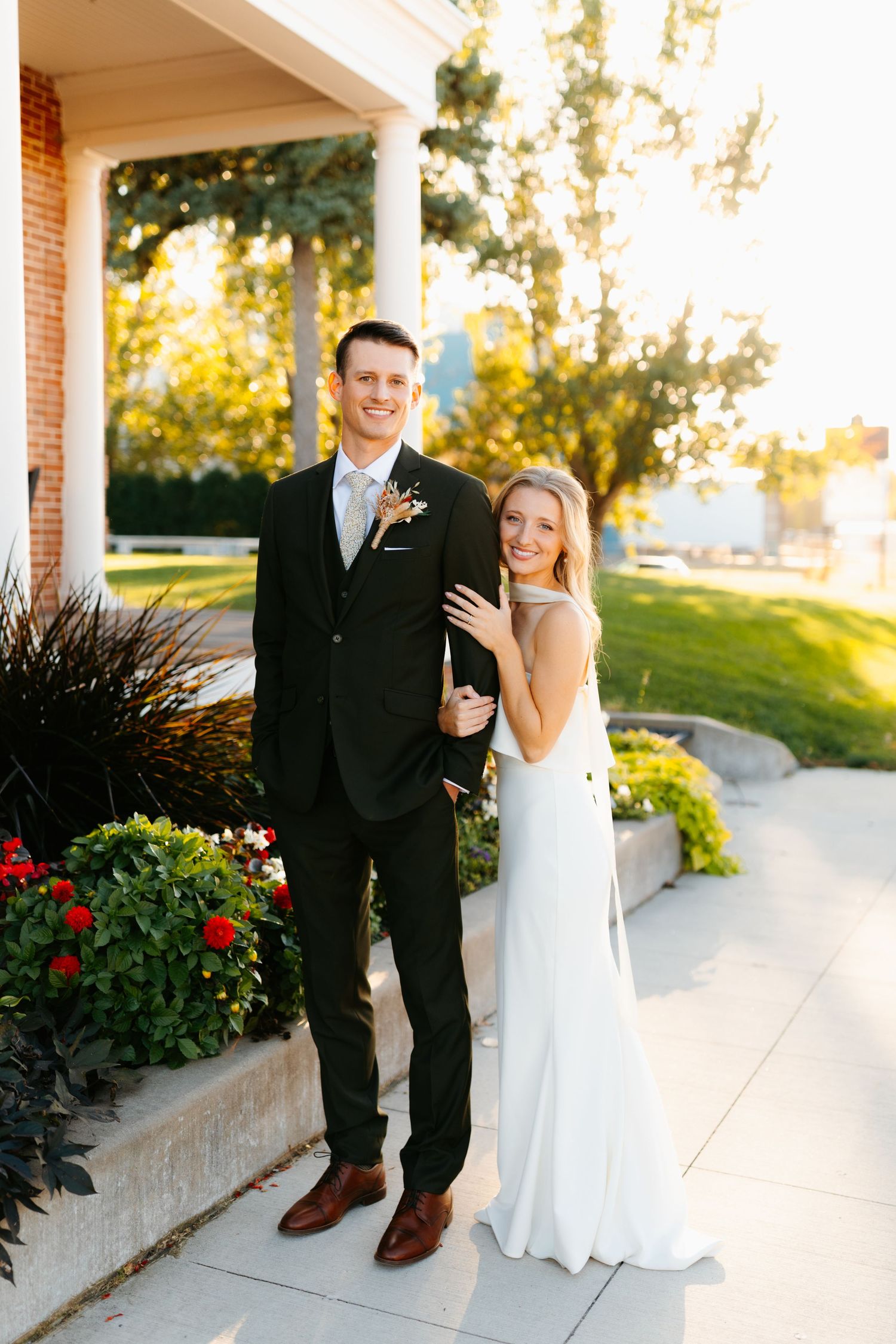 A couple shares a joyful moment together on a garden path at sunset.