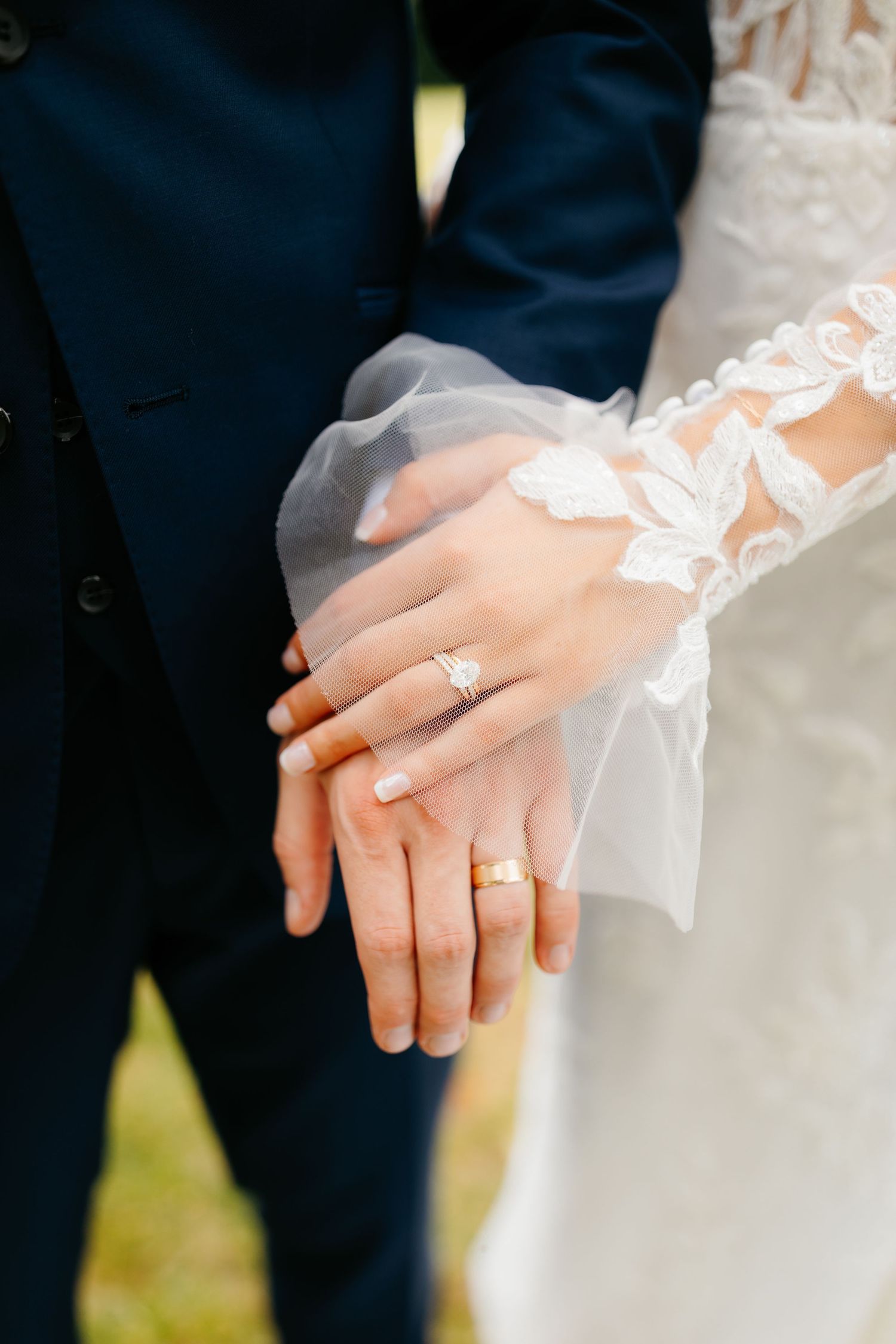 Close-up shots of hands wearing wedding rings and delicate lace sleeves during a wedding ceremony.