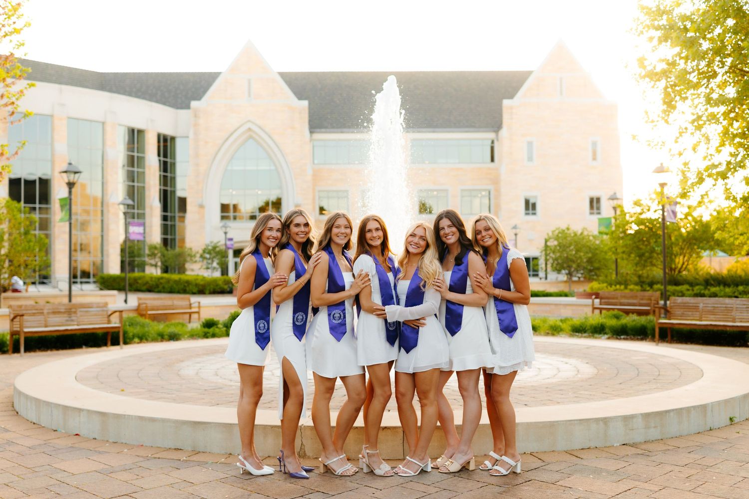 Group in coordinated blue and white outfits poses by circular fountain.