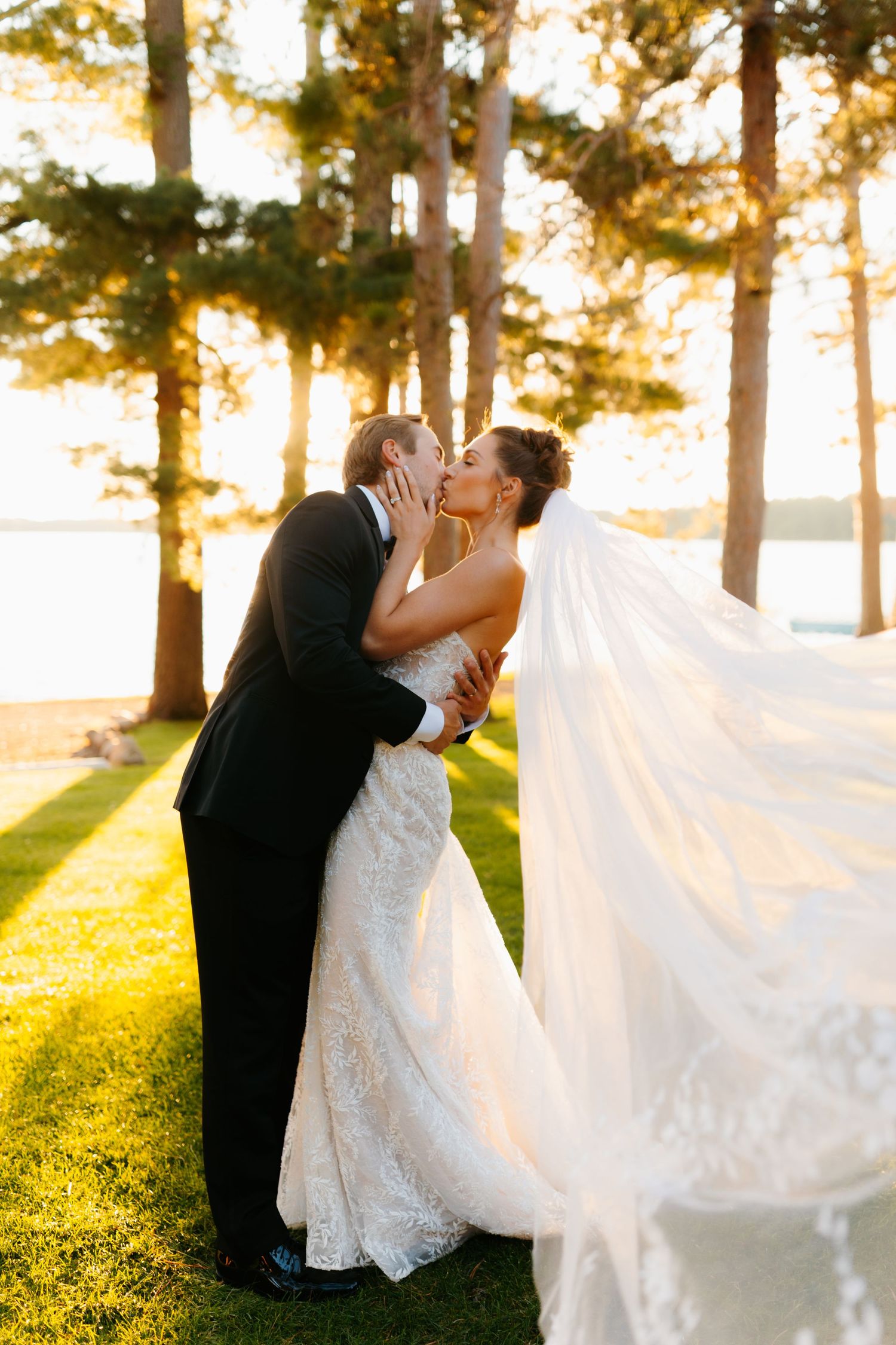 A couple shares intimate moments at sunset among tall pine trees.