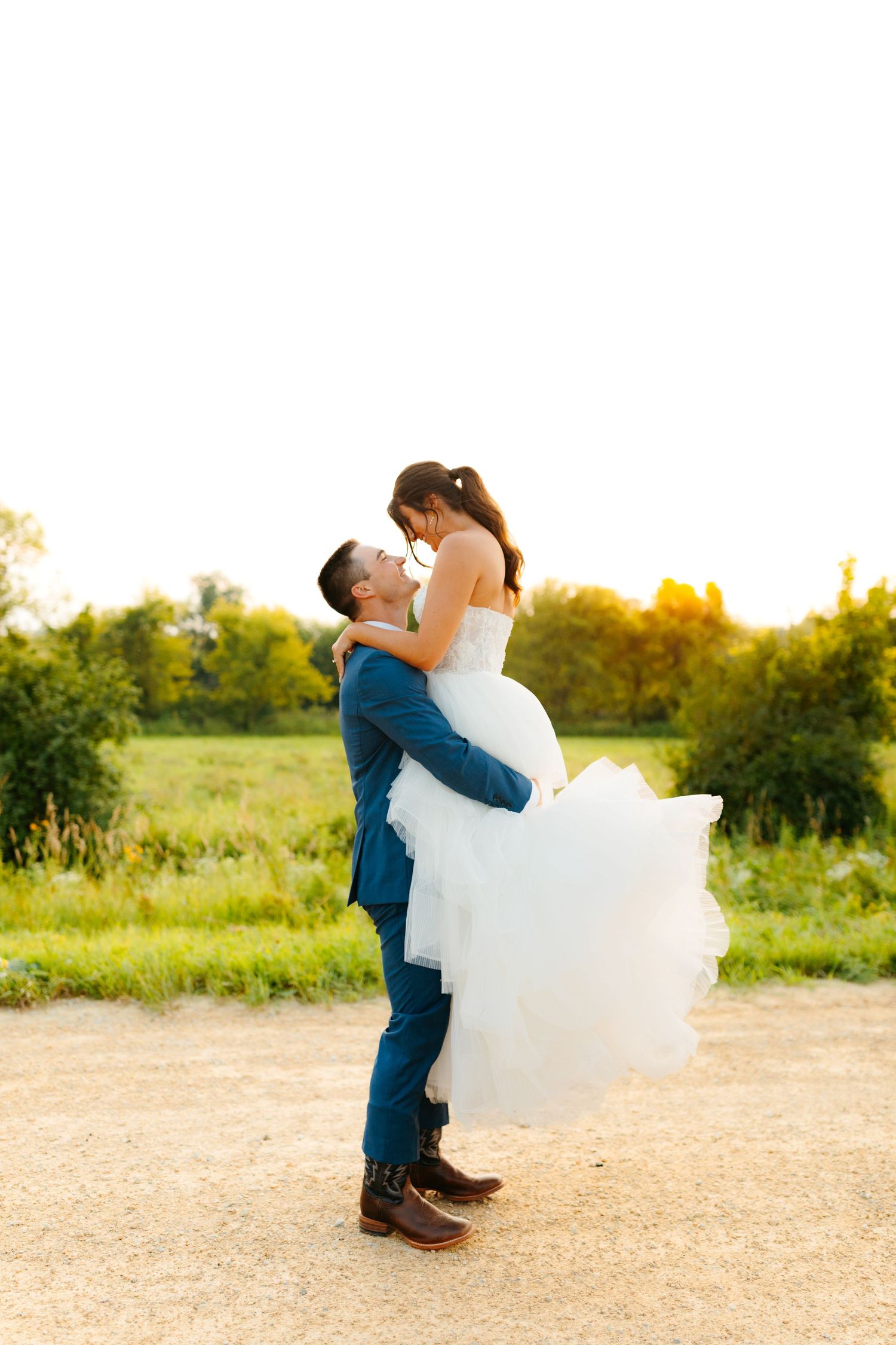 Newlyweds share a romantic dance sequence in an outdoor field during golden hour.