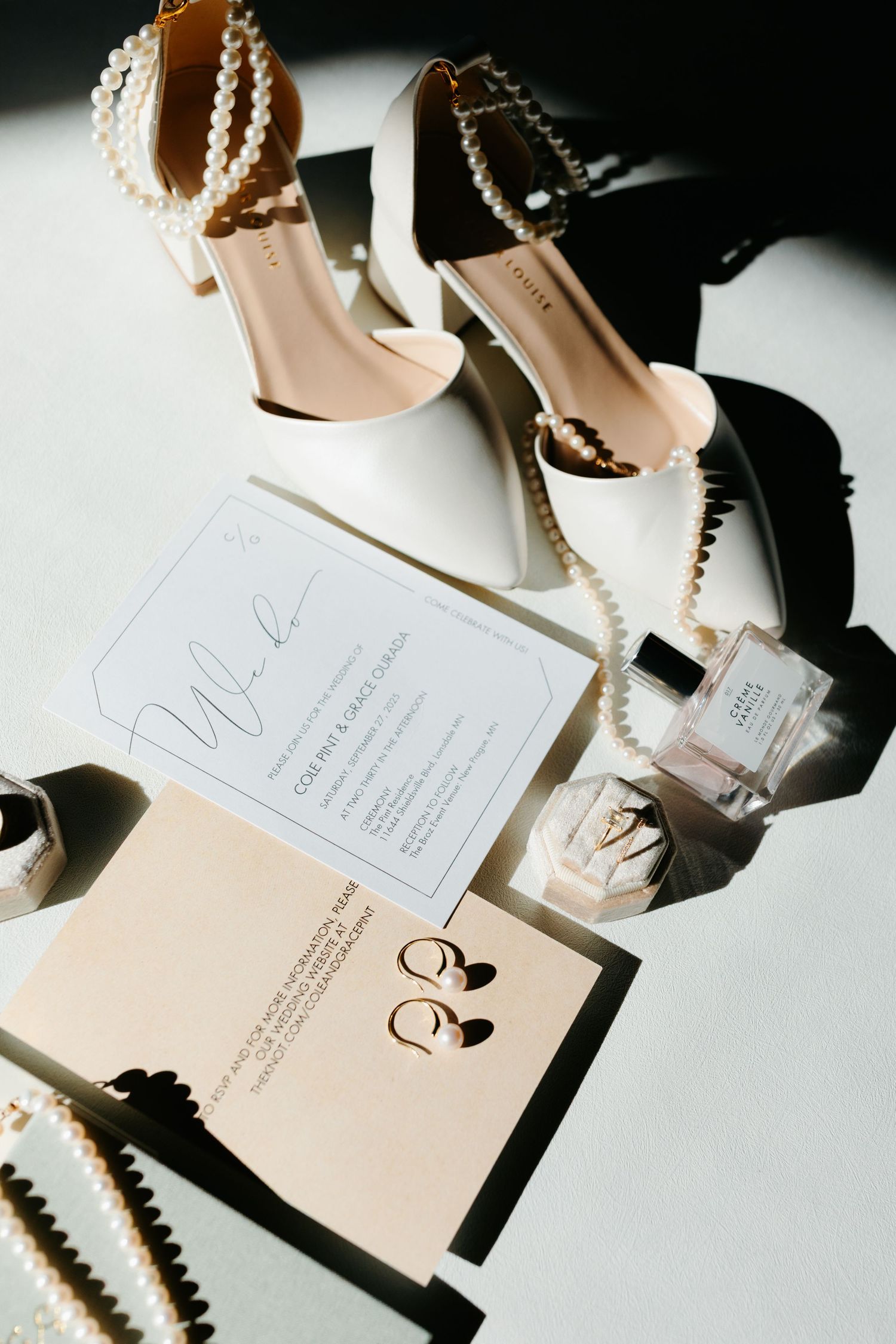 Wedding invitation suite with pearl details and high heels photographed on white background.