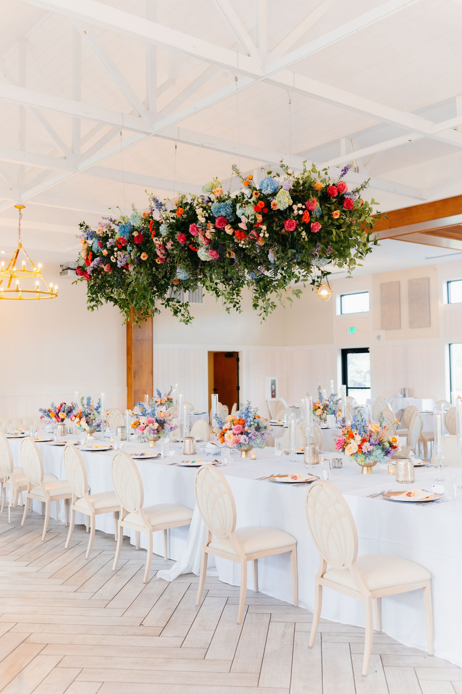 Elegant white wedding reception venue with floral ceiling installations and crisp table settings.