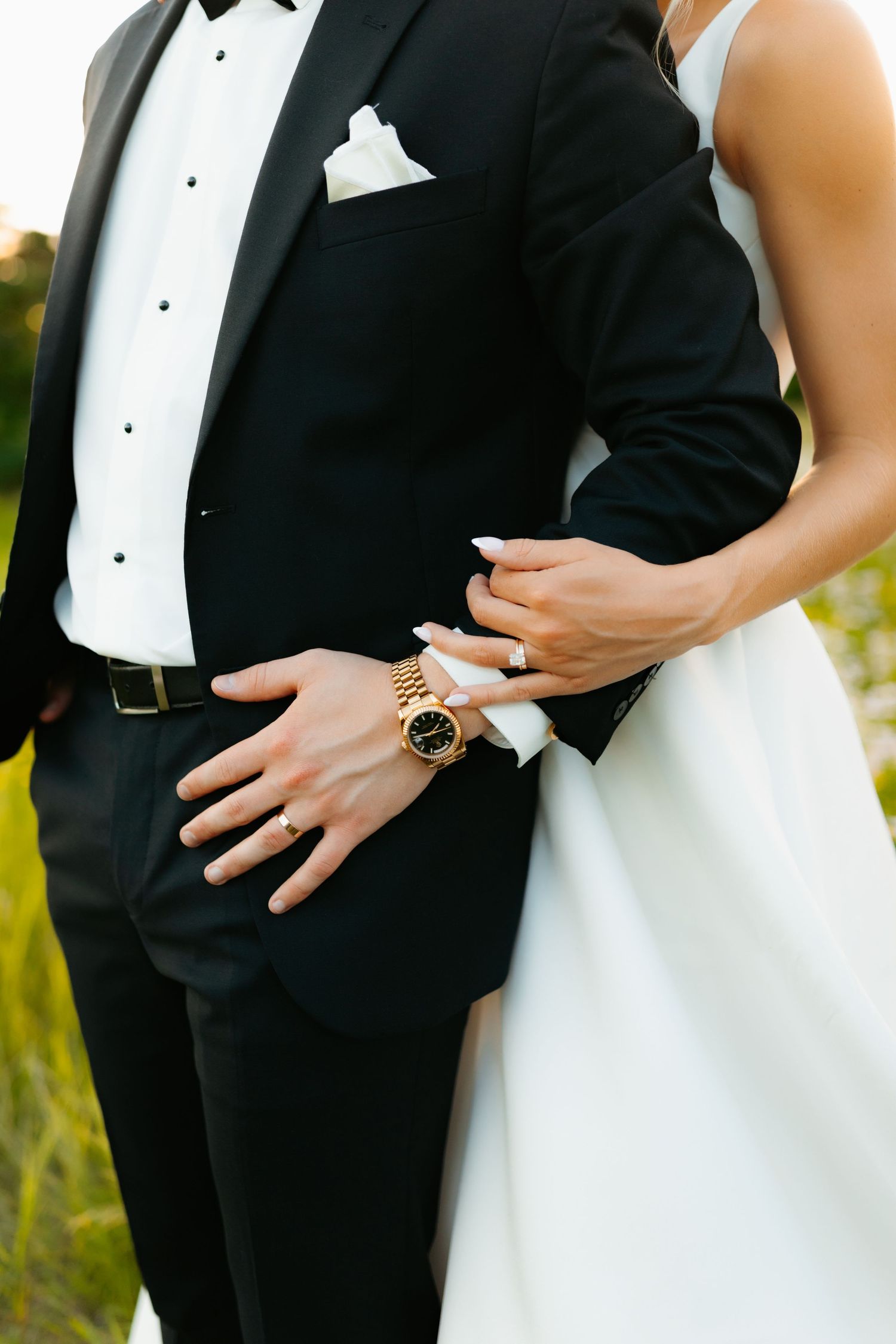 Close-up details of formal wedding attire with tuxedo and white dress.