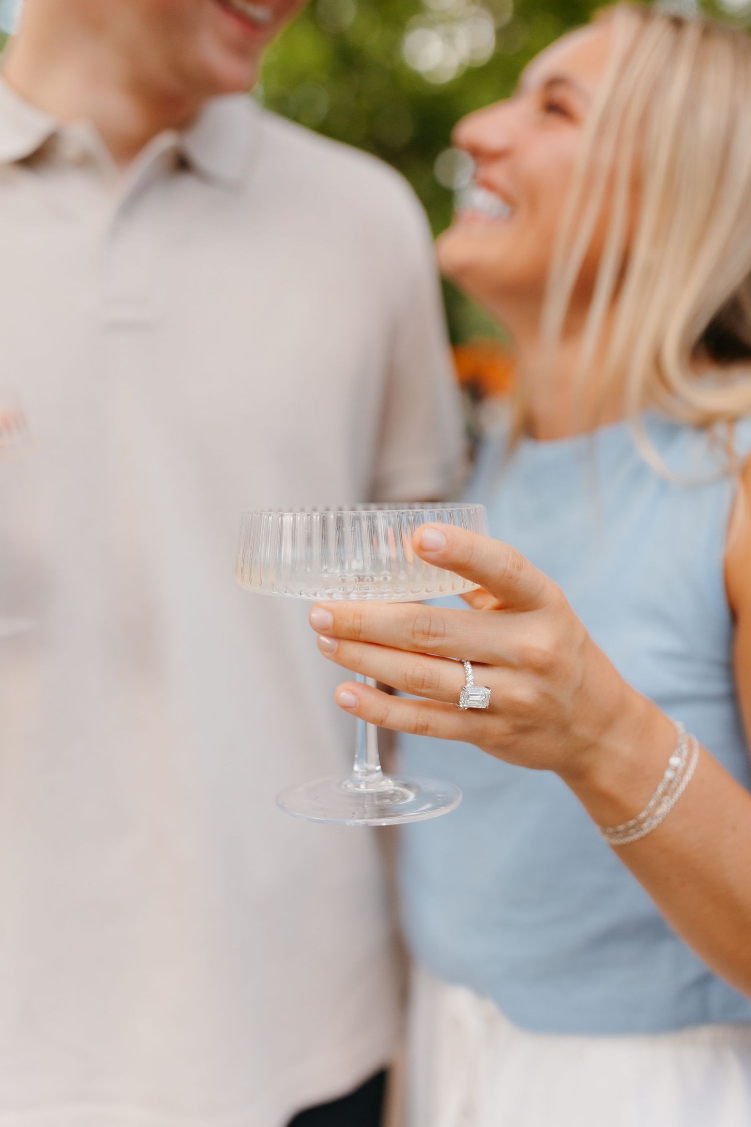 Elegant champagne glasses being held during a wedding celebration with light blue attire details.
