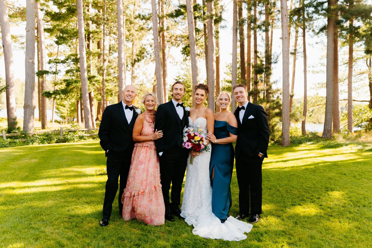 Wedding party poses among tall birch trees on a sunny afternoon.