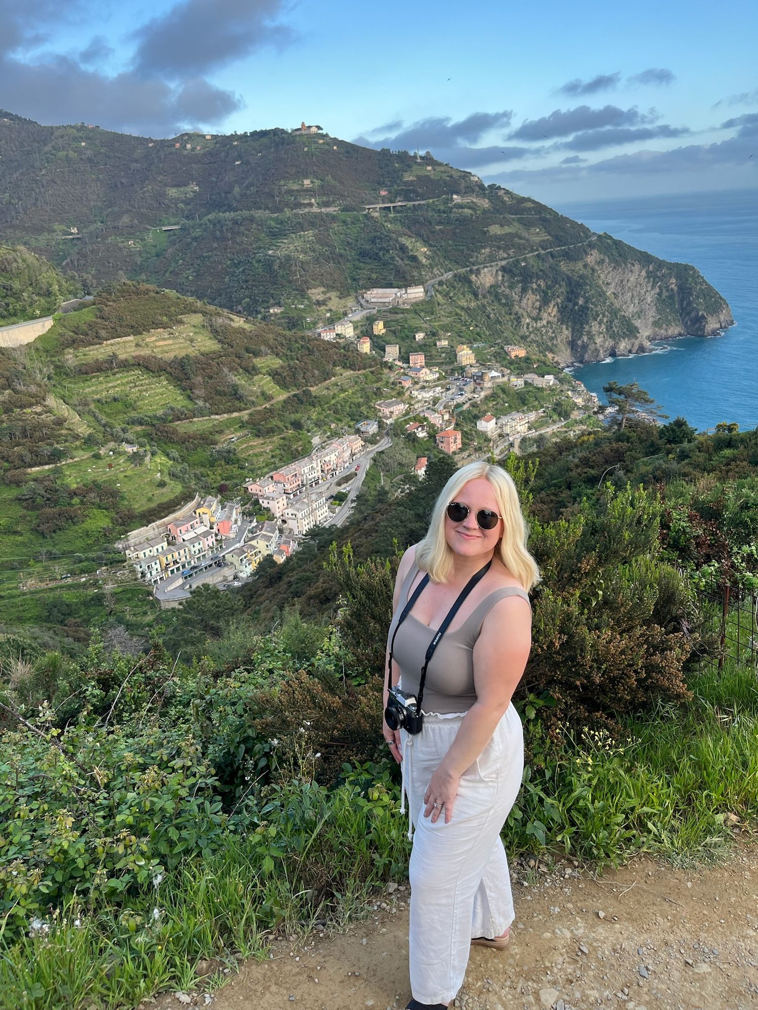 Scenic coastal view of Cinque Terre villages along Italian cliffside with photographer in foreground.