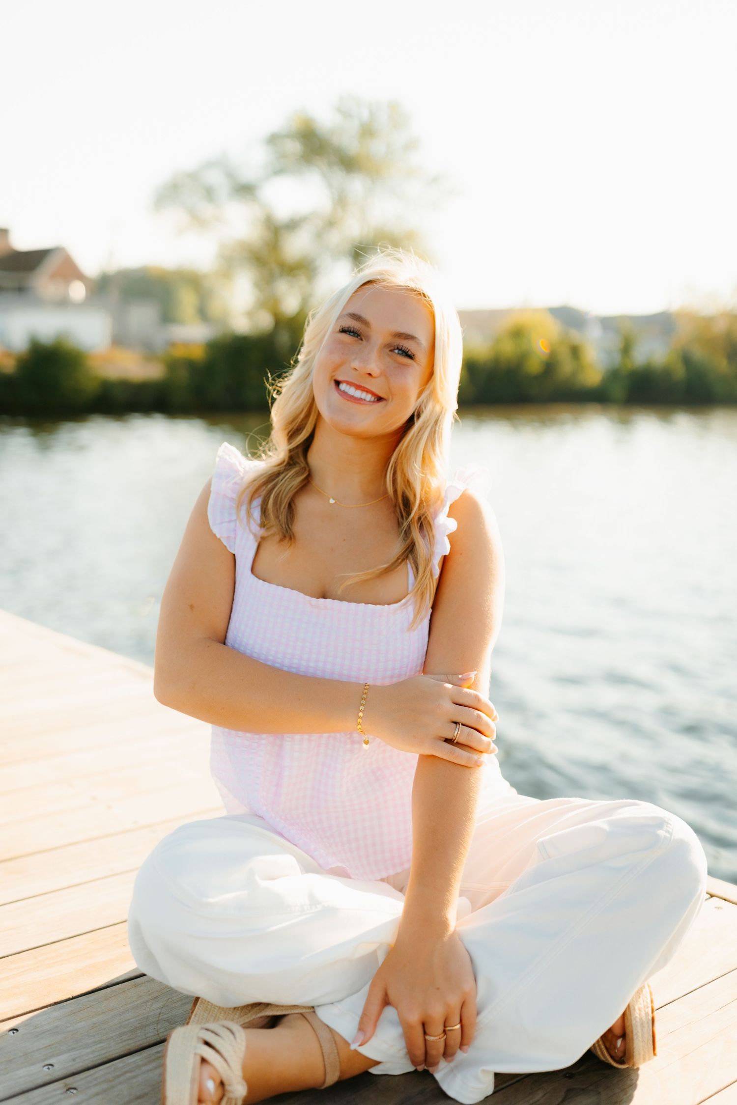 Summer portrait session on wooden dock by serene lake at sunset.