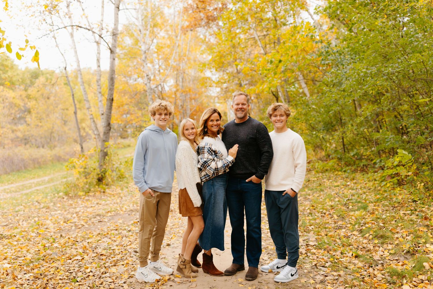 Family portrait session in a park during autumn with fall foliage.