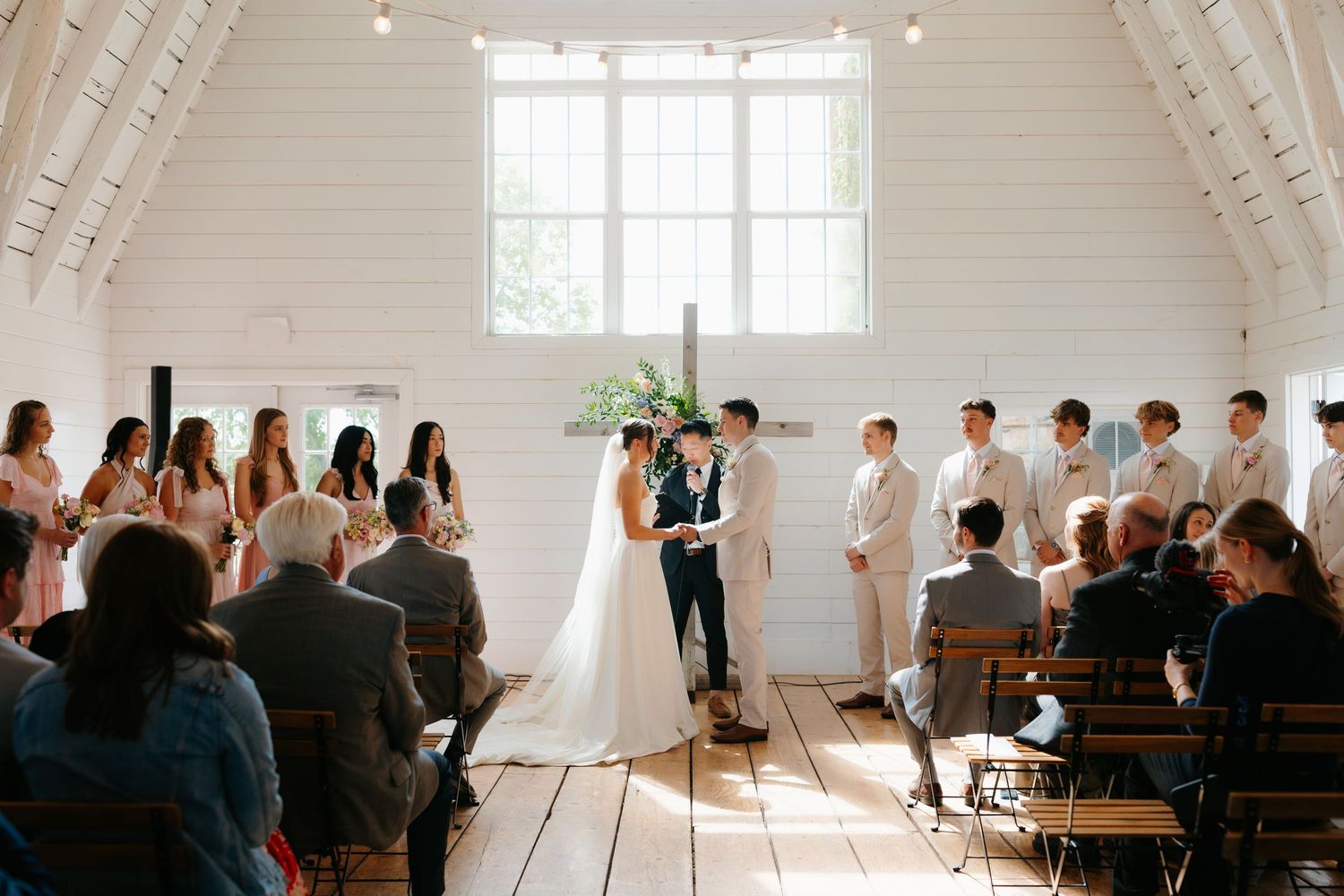 Modern white chapel interior with wooden benches and natural light streaming through windows.