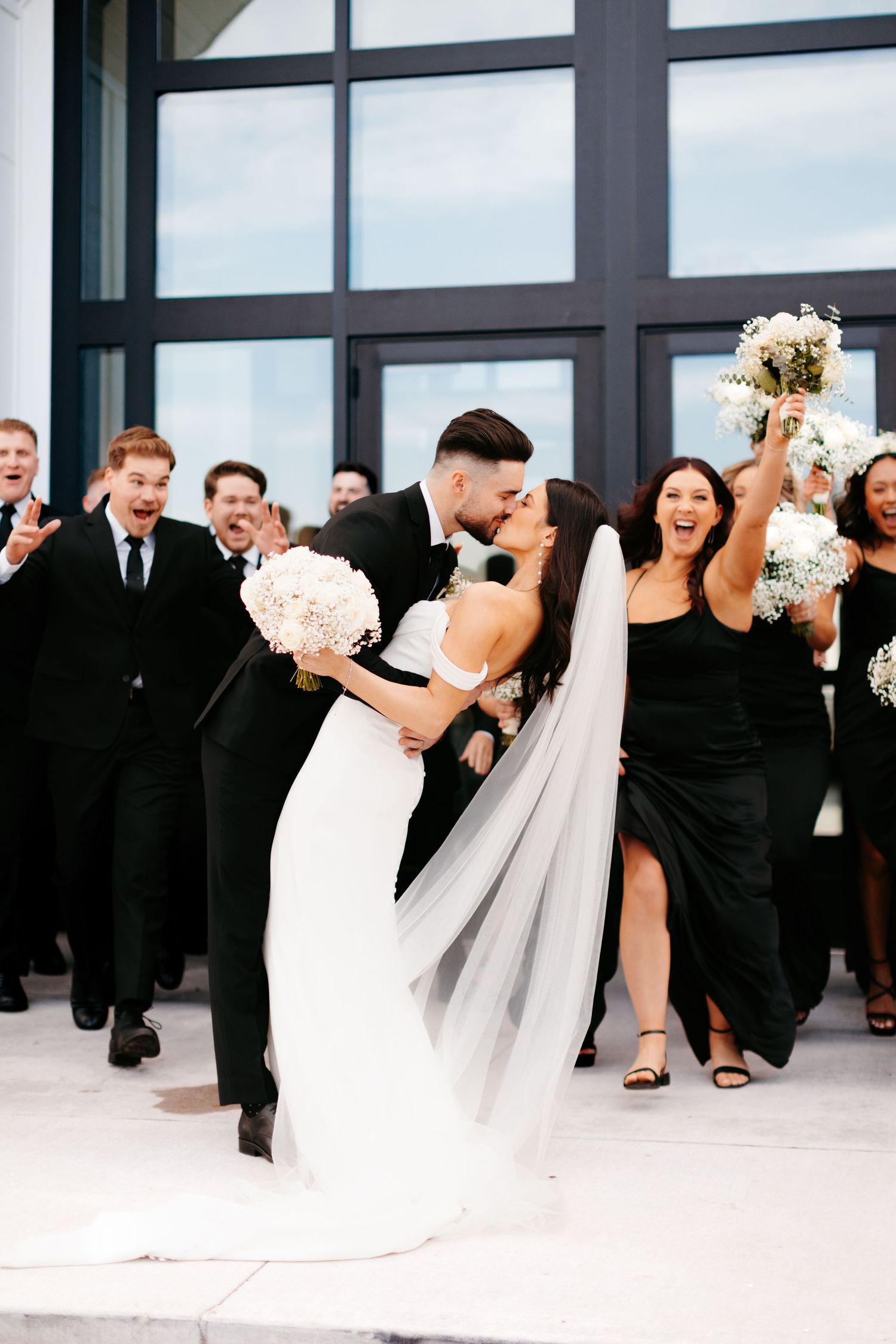 Wedding party celebrates with joyful dance moves in formal attire.