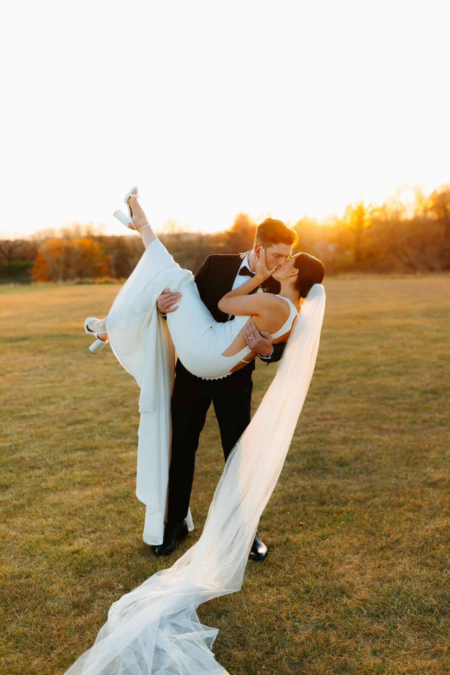 Dramatic sunset wedding dip pose in golden field.