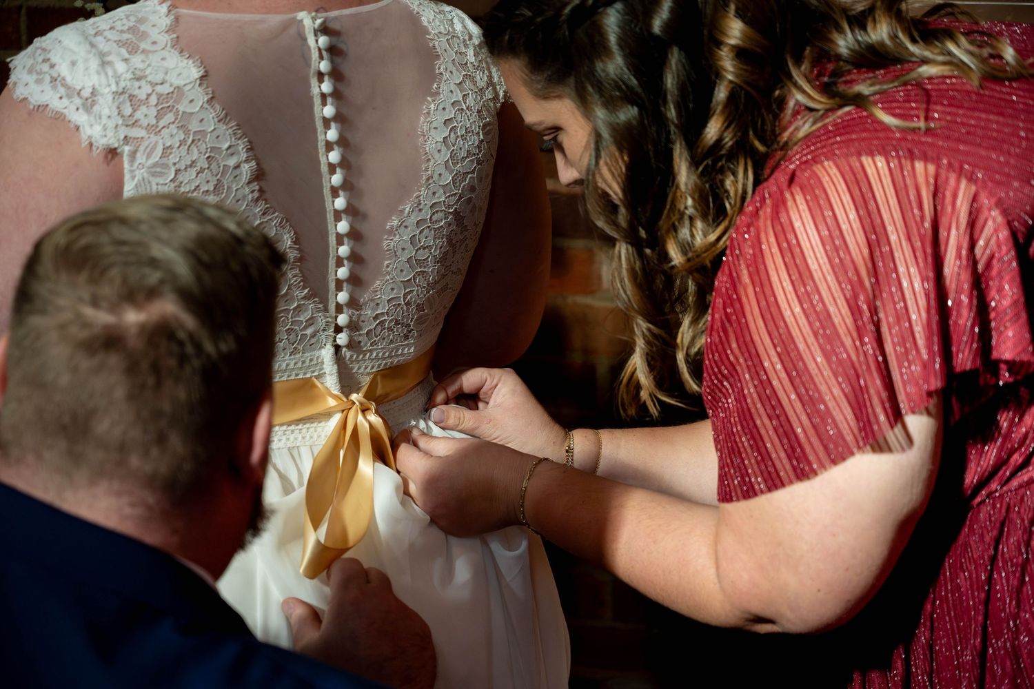 Close up of Bridesmaid and groom bustling brides train