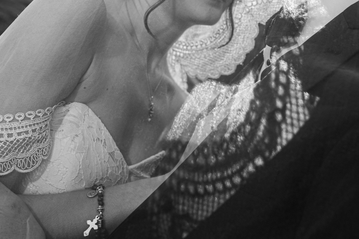 Black and white close up lace veil shadow on grooms lapel.