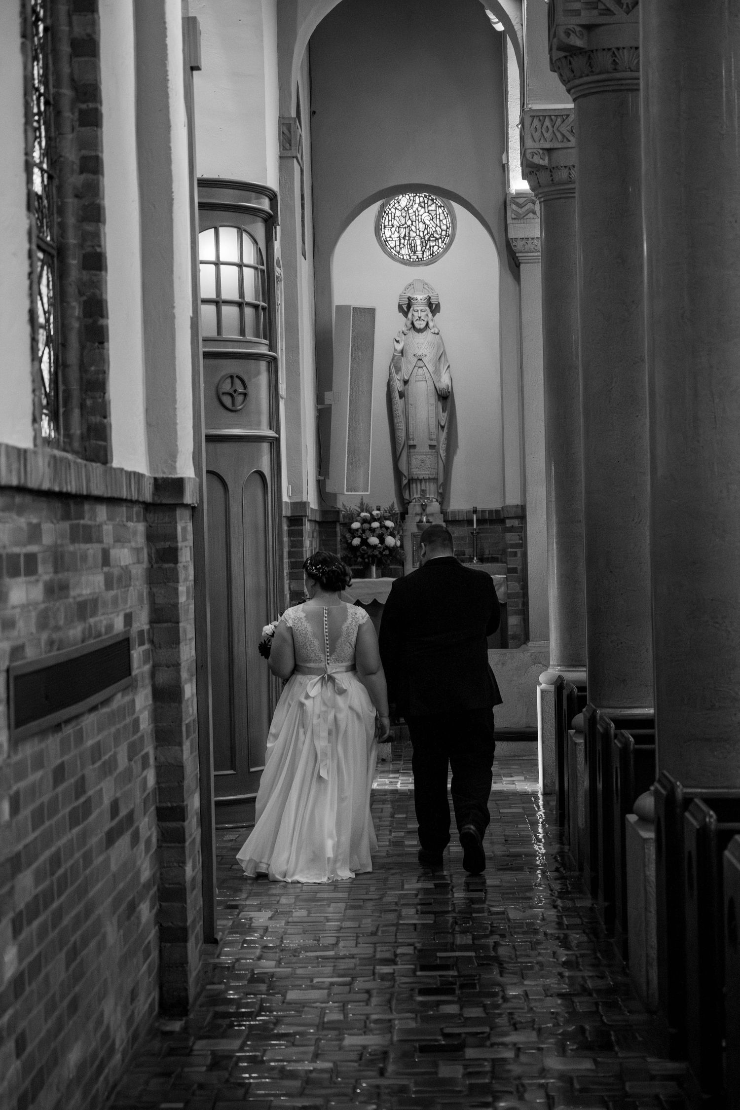 Black and white of bride and groom waling down the side aisle of Saint Benedict Catholic Church Richmond Virginia