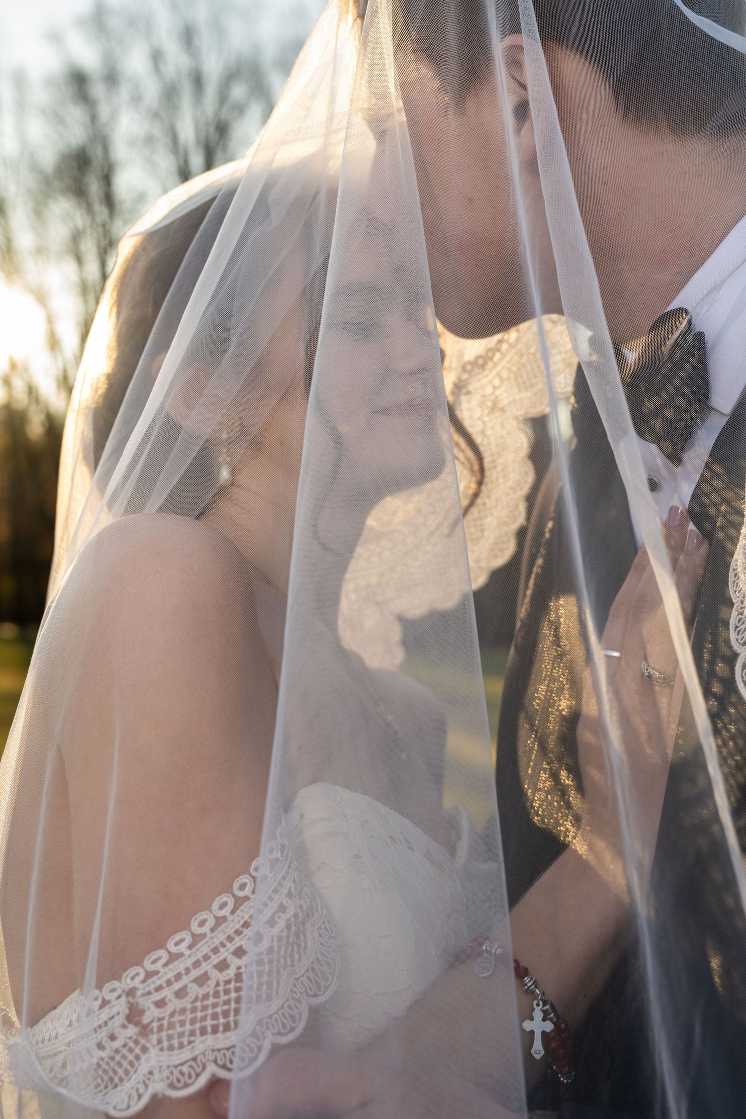 Bride and groom under veil warm sunshine groom kisses brides forehead. Stevenson Ridge wedding venue Spotsylvania Virginia