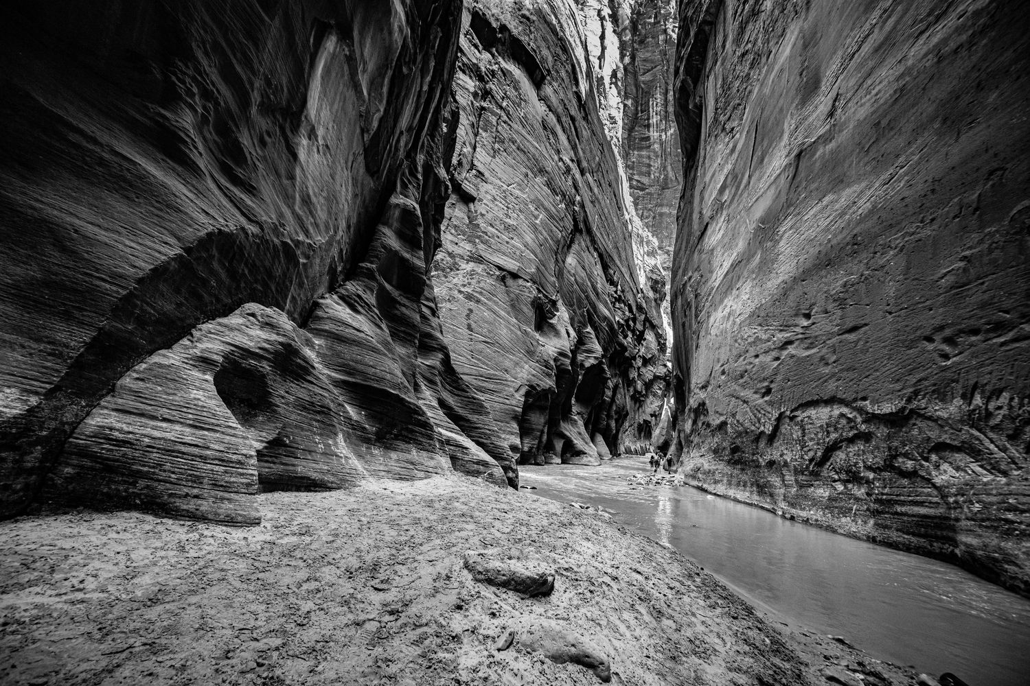Dramatic black and white images of narrow slot canyon passages with natural light beams.