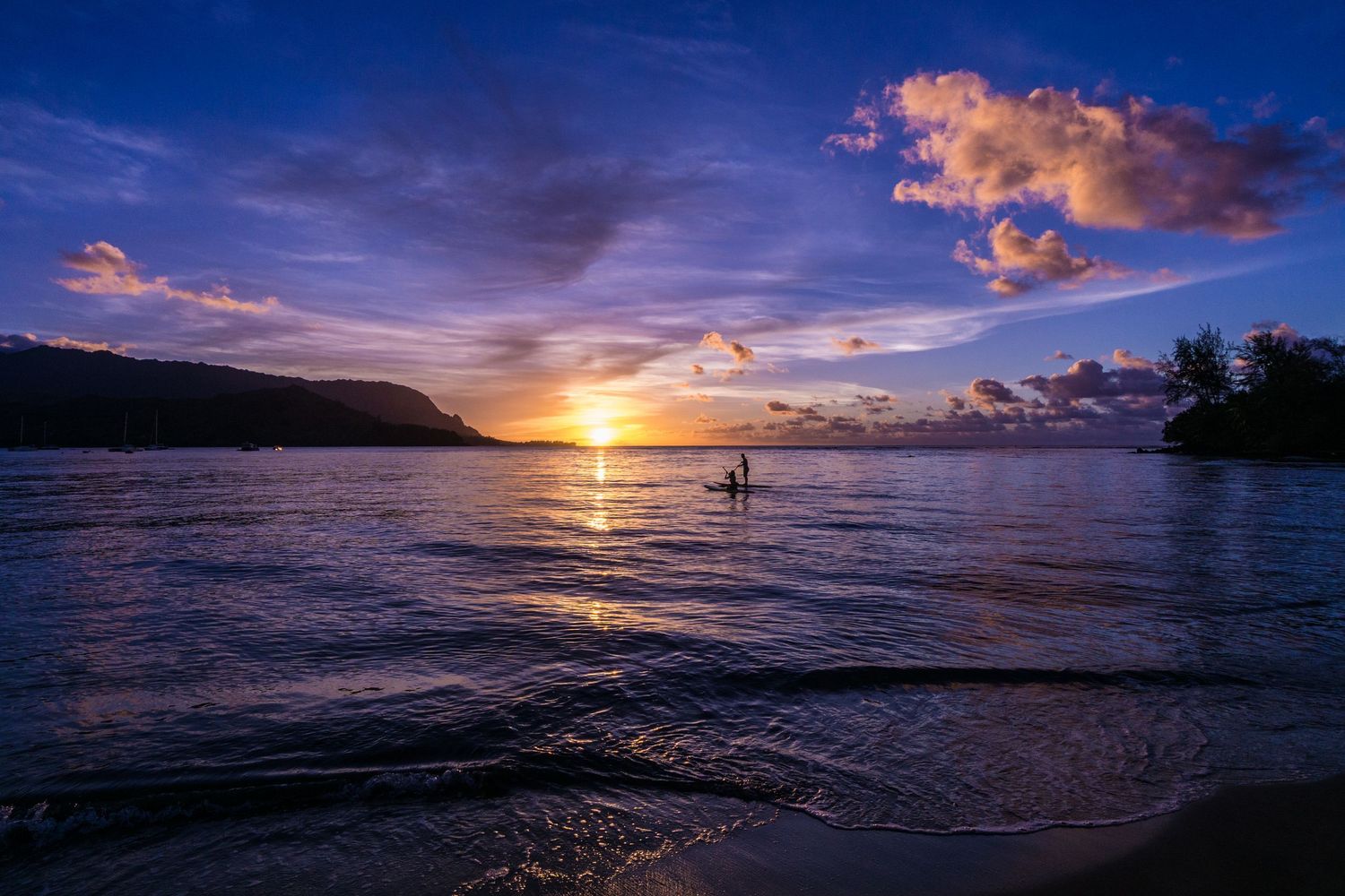 Stunning sunset over the ocean with dramatic clouds and golden light reflecting on calm waters.