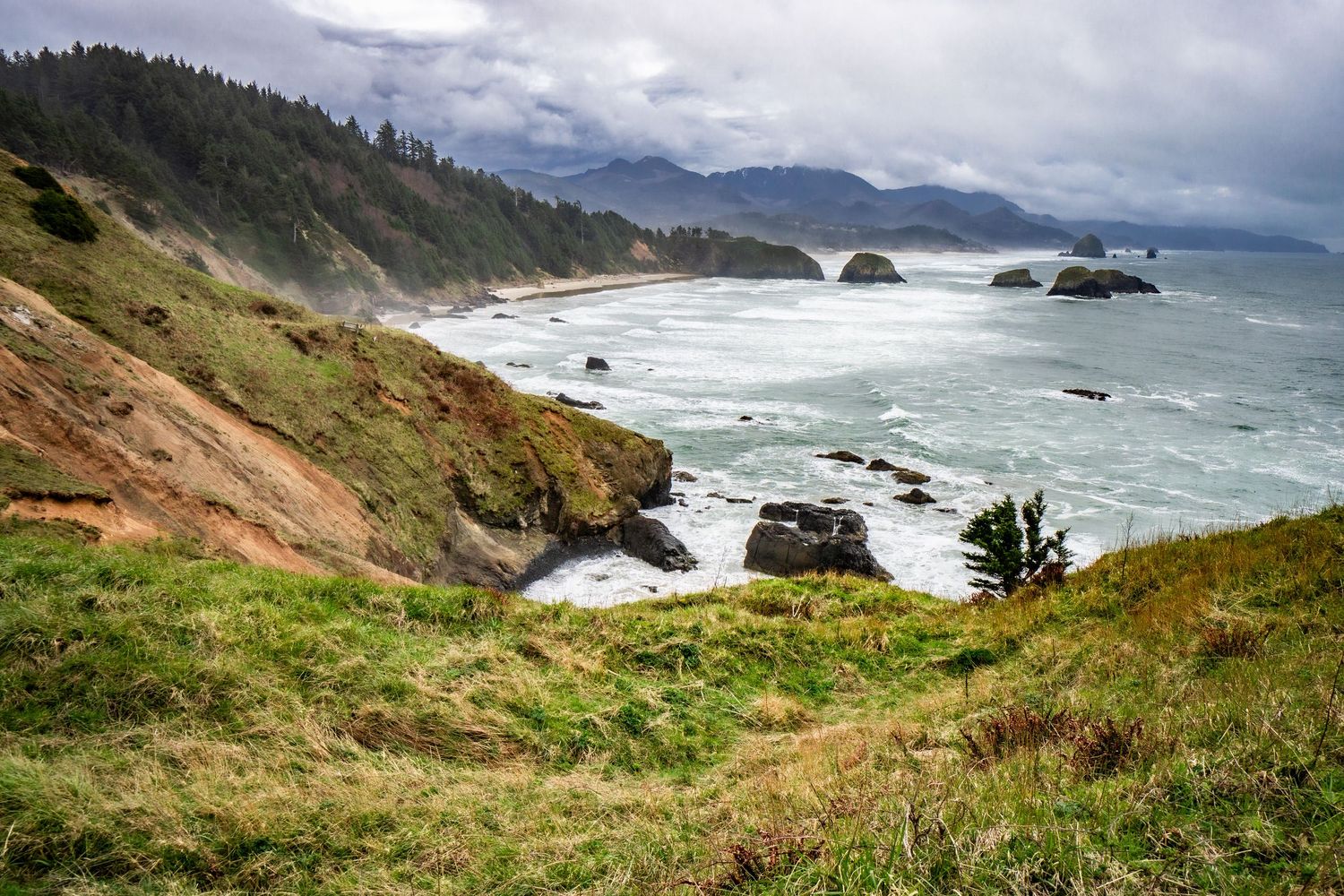 Dramatic coastal landscape with rugged cliffs, crashing waves, and rocky outcrops along the Pacific Northwest shoreline.