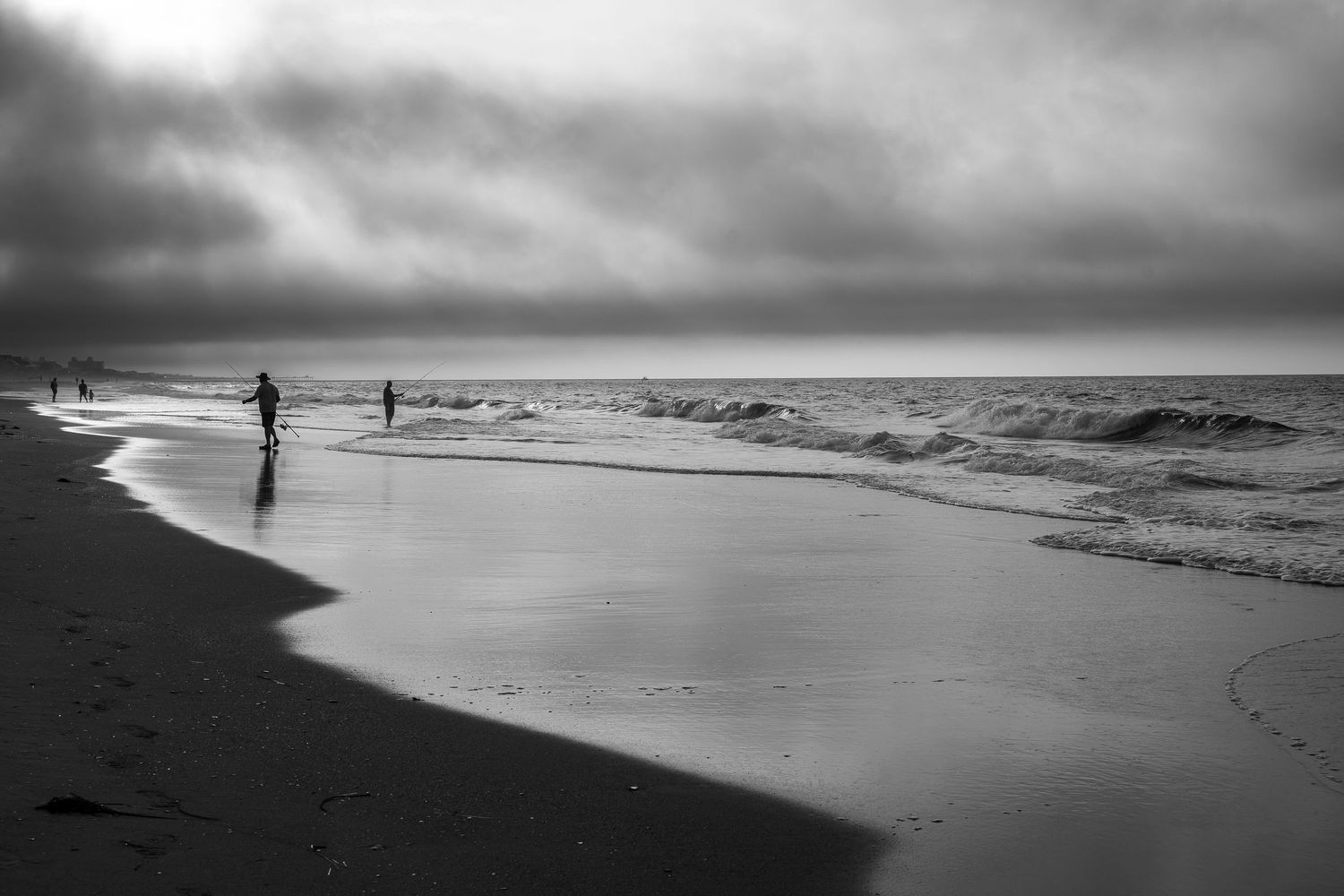 Minimalist black and white seascape with distant figures walking along misty shoreline.