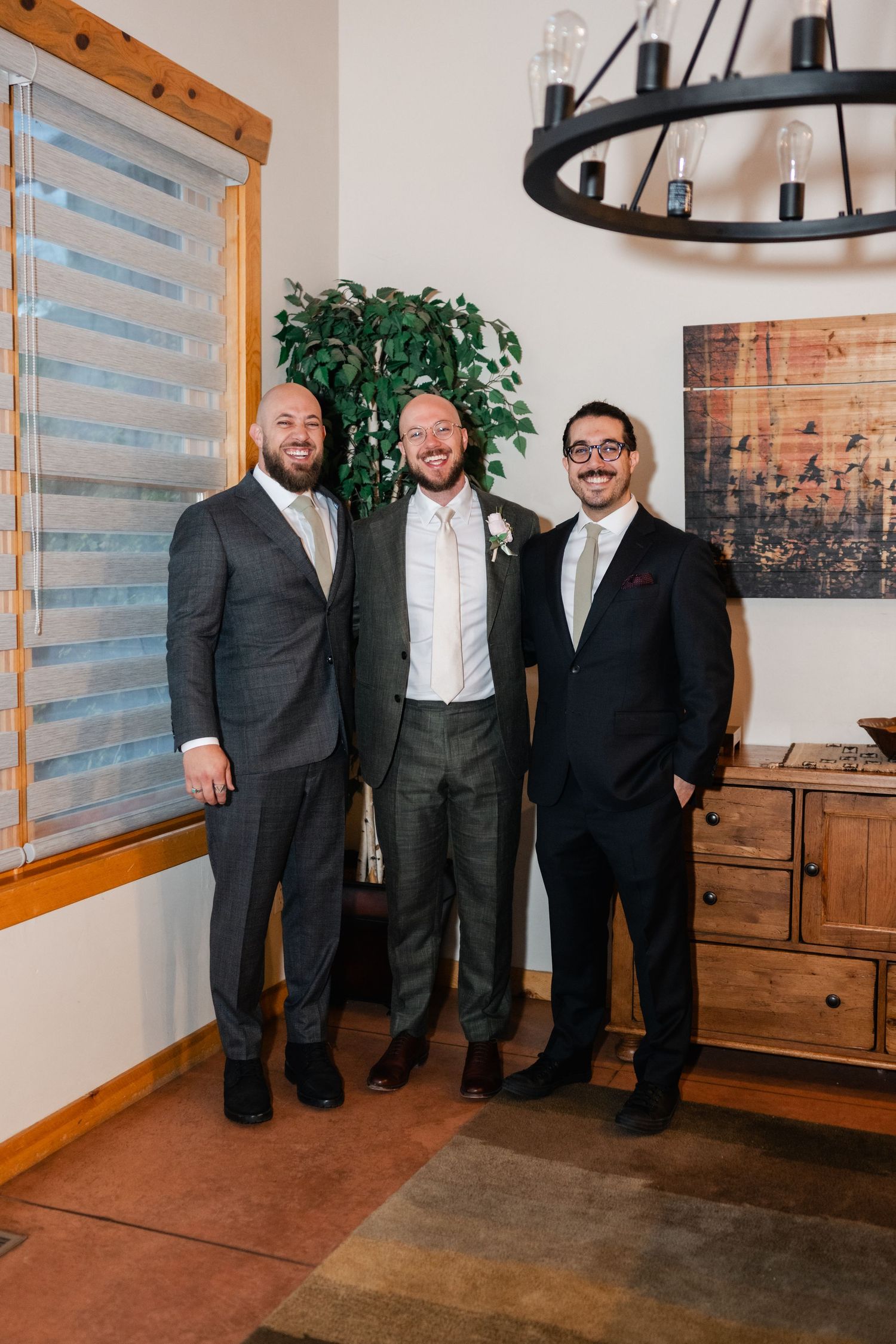 Groomsmen in formal attire pose together in a rustic indoor setting.