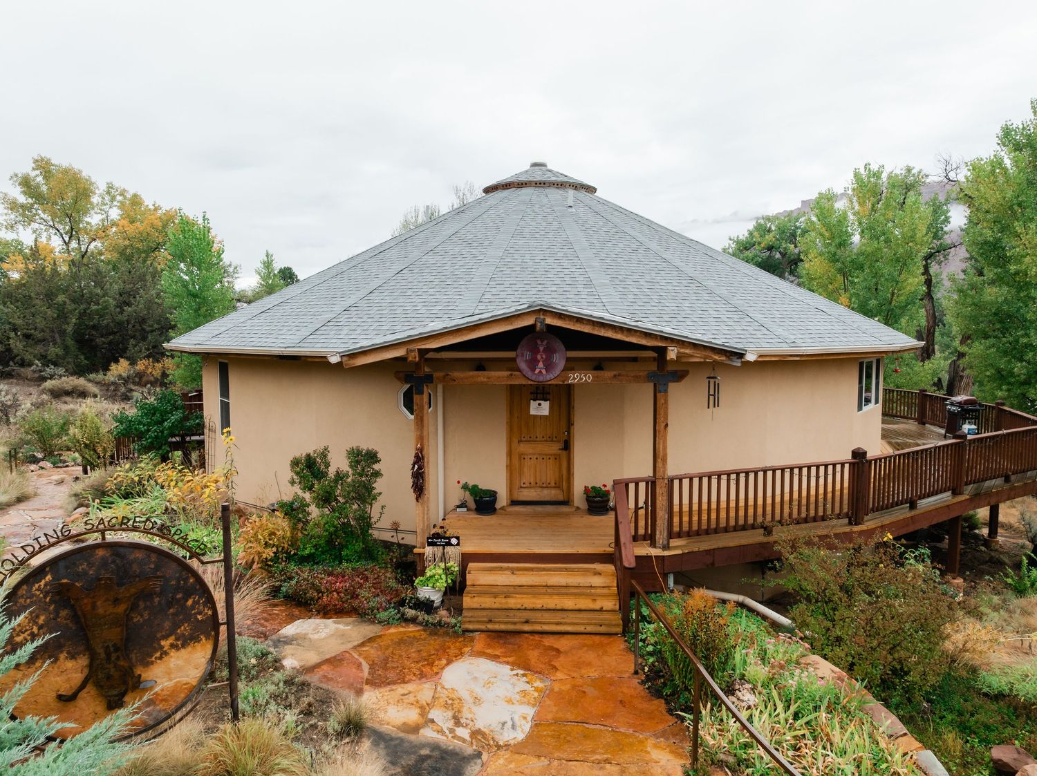 Panoramic view of a modern rustic home with multiple exterior angles showing wood decking and desert landscape surroundings.