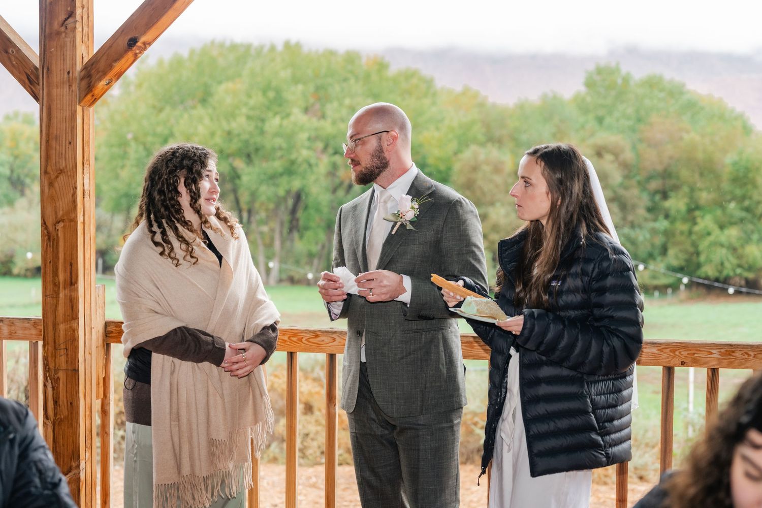 Groups of people socializing on a wooden deck with mountain views.