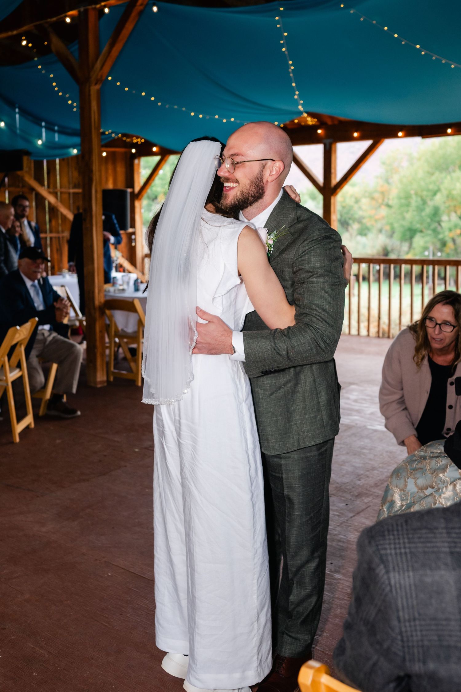 Wedding celebration in a rustic barn venue with string lights and wooden posts.