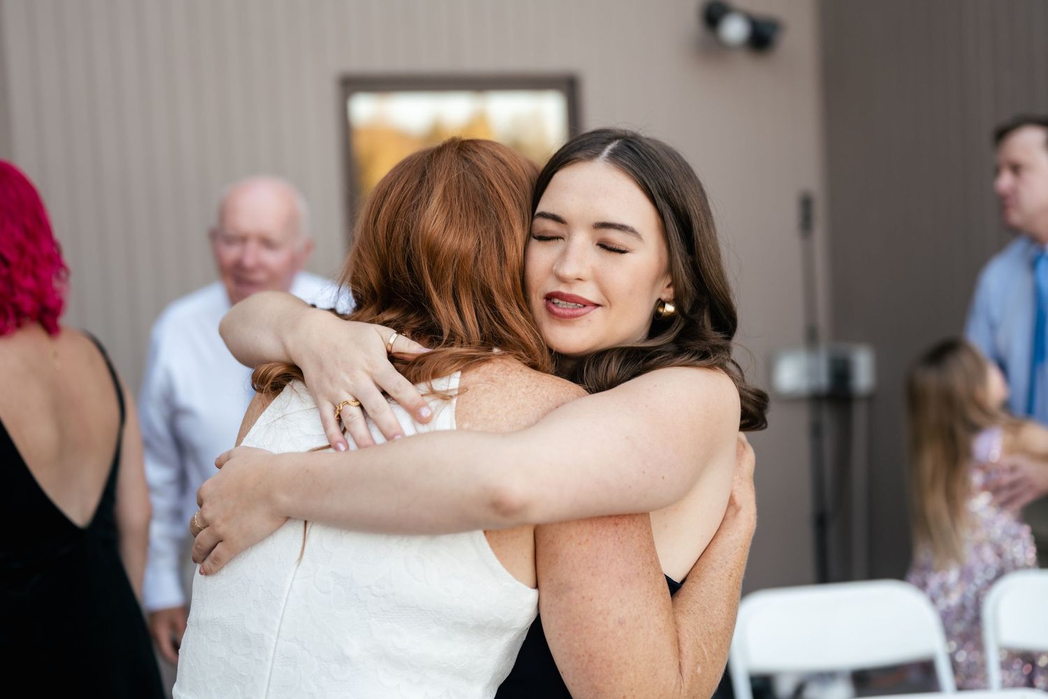 Emotional embrace shared between two guests during a wedding celebration indoors.