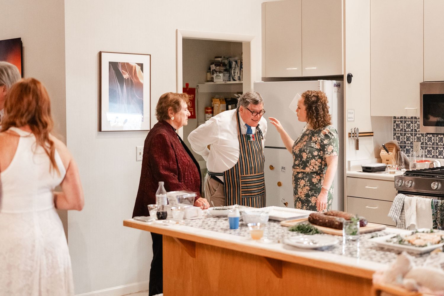 Wedding reception gathering in a modern kitchen with guests mingling around the counter space.