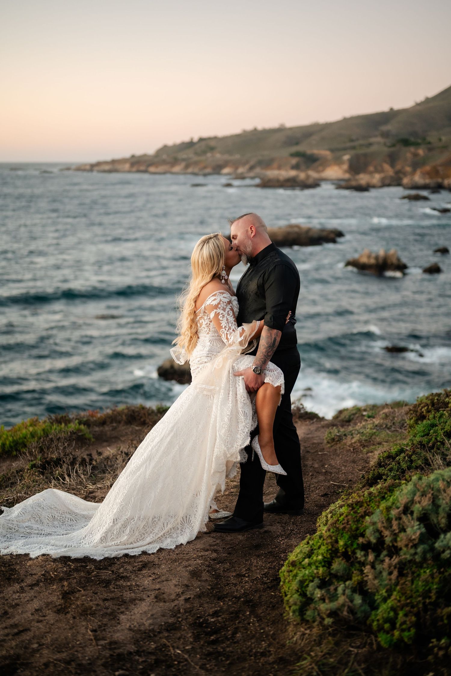 A dramatic clifftop wedding photo with waves crashing against rocky coastline.