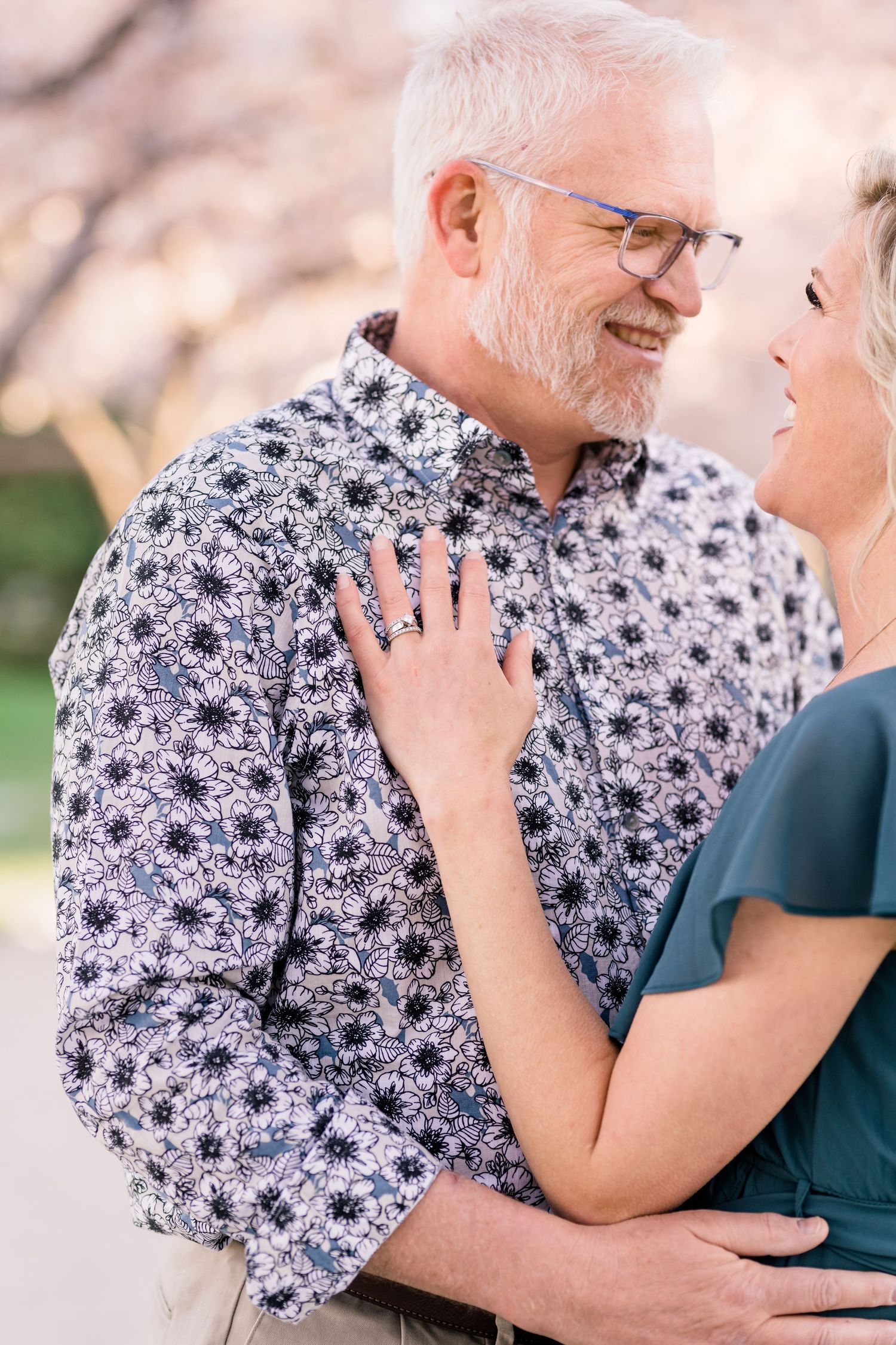 Engaged couple hug warmly at the Capitol cherry blossoms by Utah wedding photographer Coley Cook