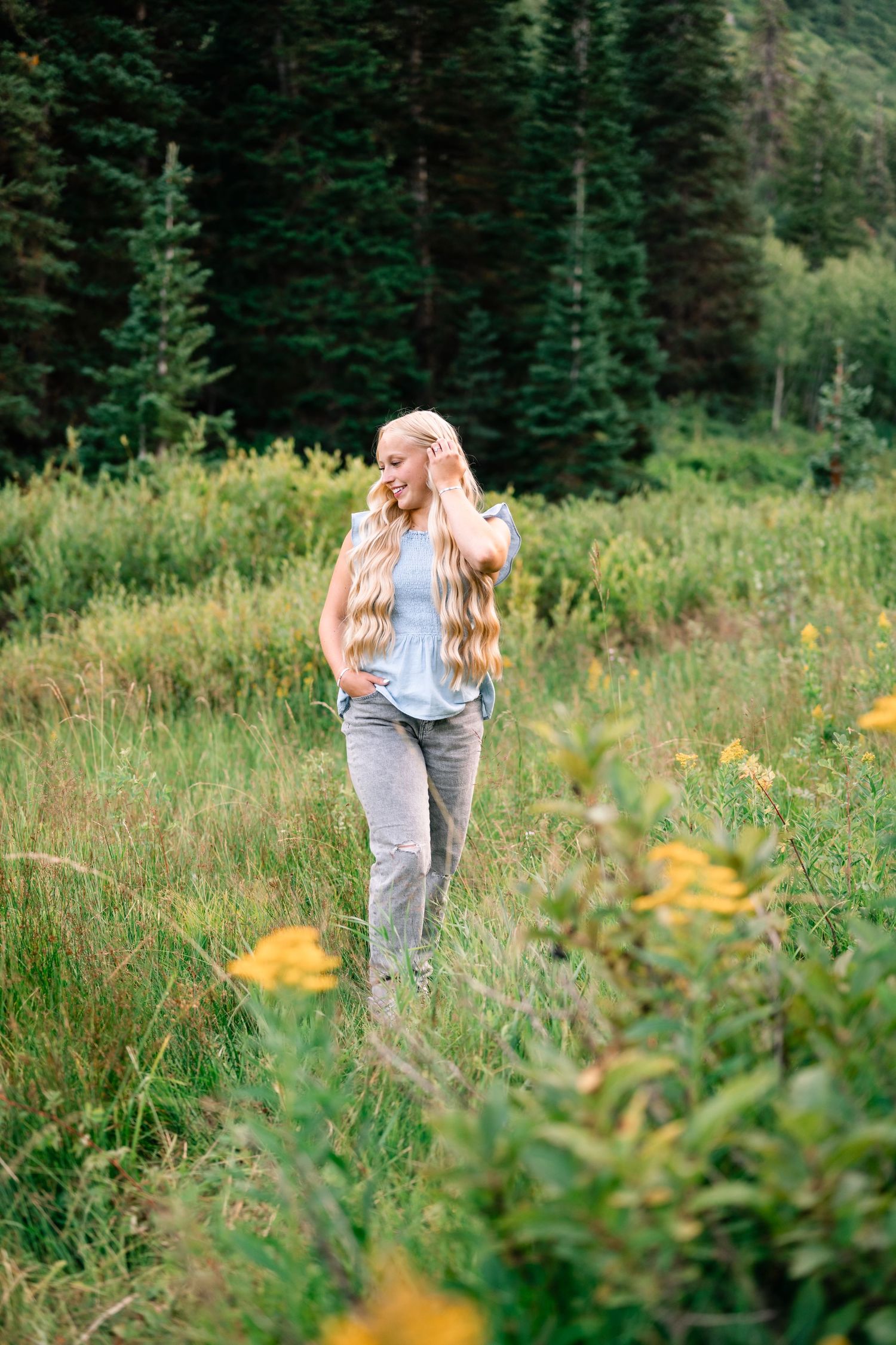 senior girl walking through a mountain meadow during her summer senior session