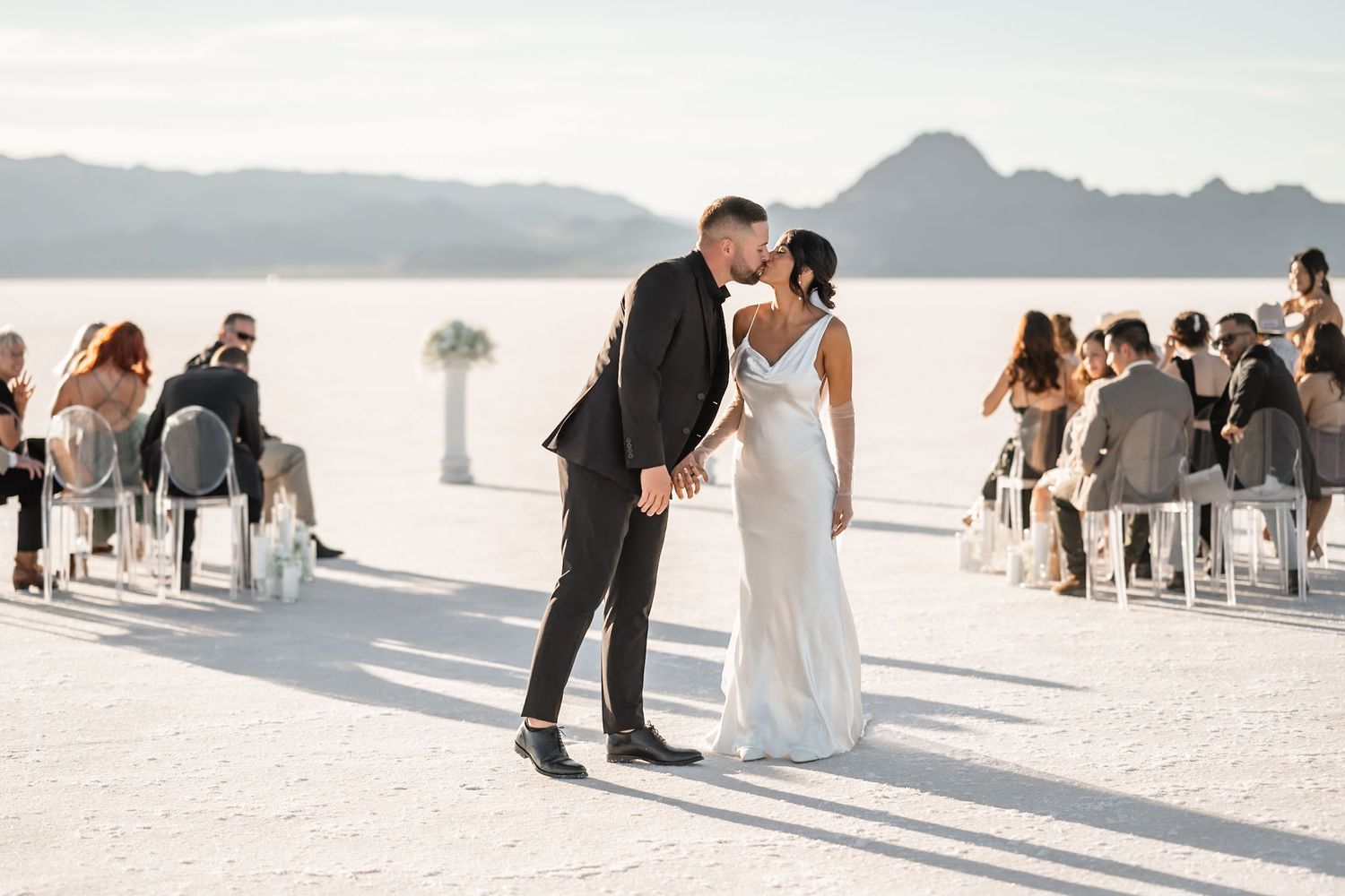 Wedding ceremony in progress on vast salt flats with mountains in background.