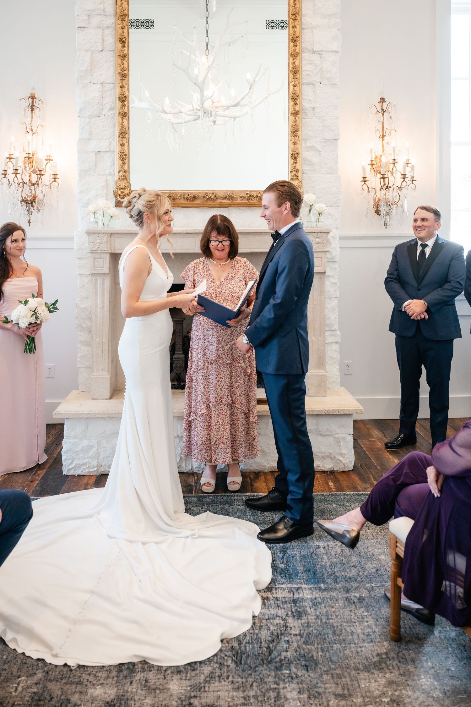 Wedding ceremony taking place in an elegant white room with crystal chandeliers. Washington School House Hotel ceremony. Park City Wedding.