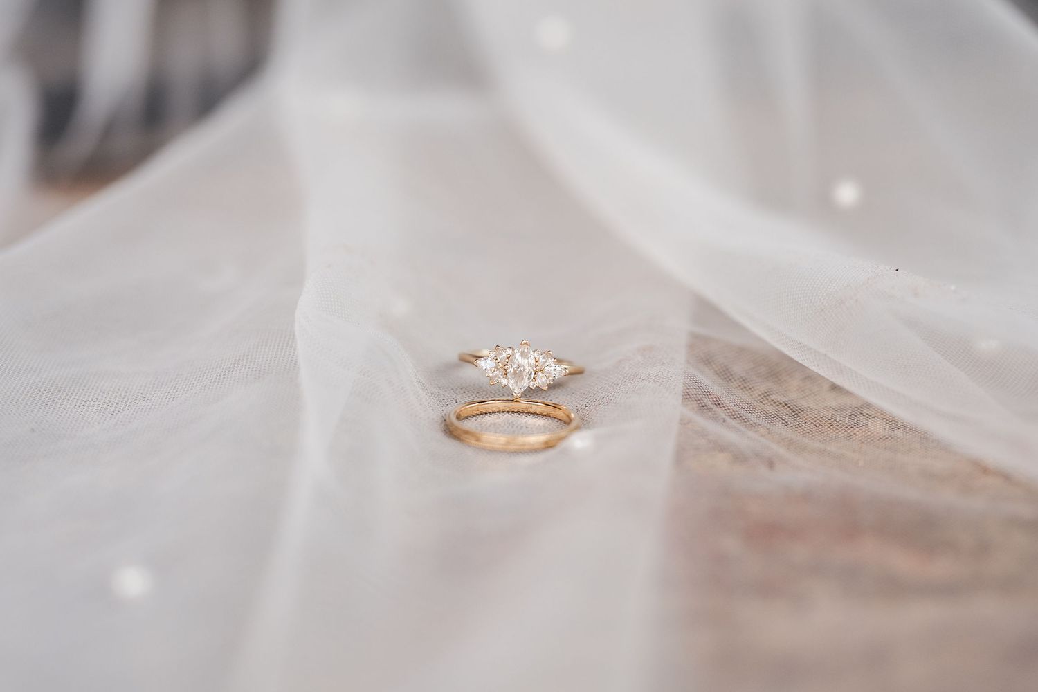 Elegant rose gold wedding rings resting on delicate white tulle fabric.