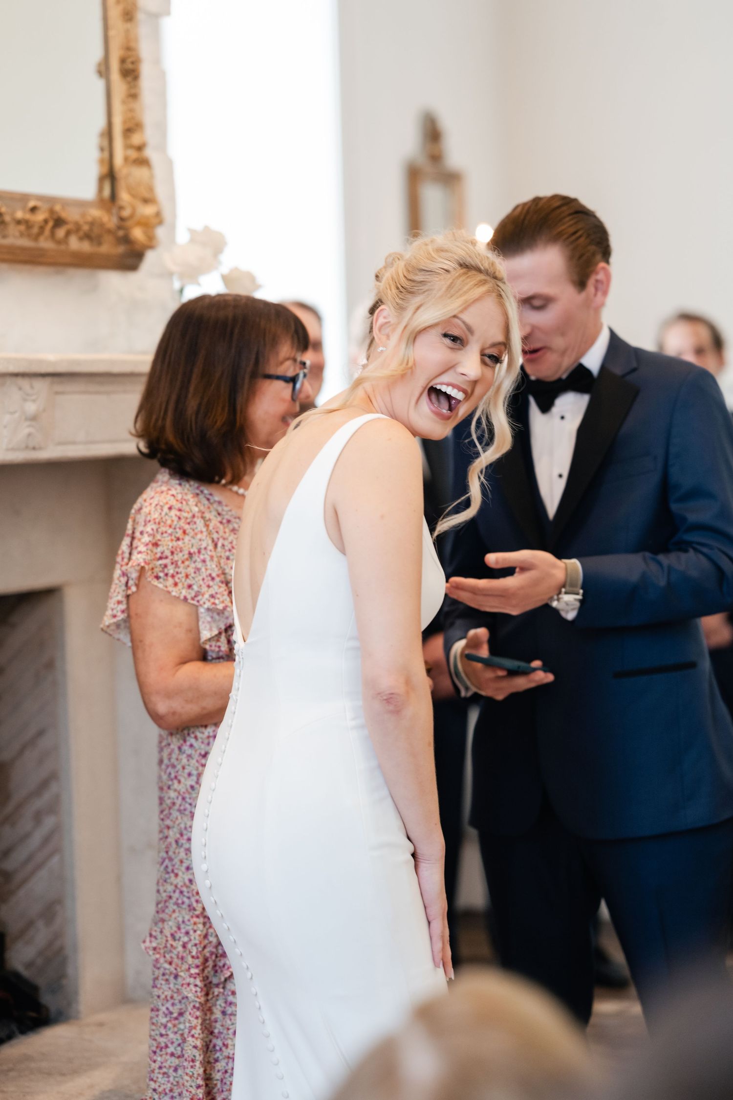 Candid moments captured during a wedding celebration in an elegant white room with ornate details.