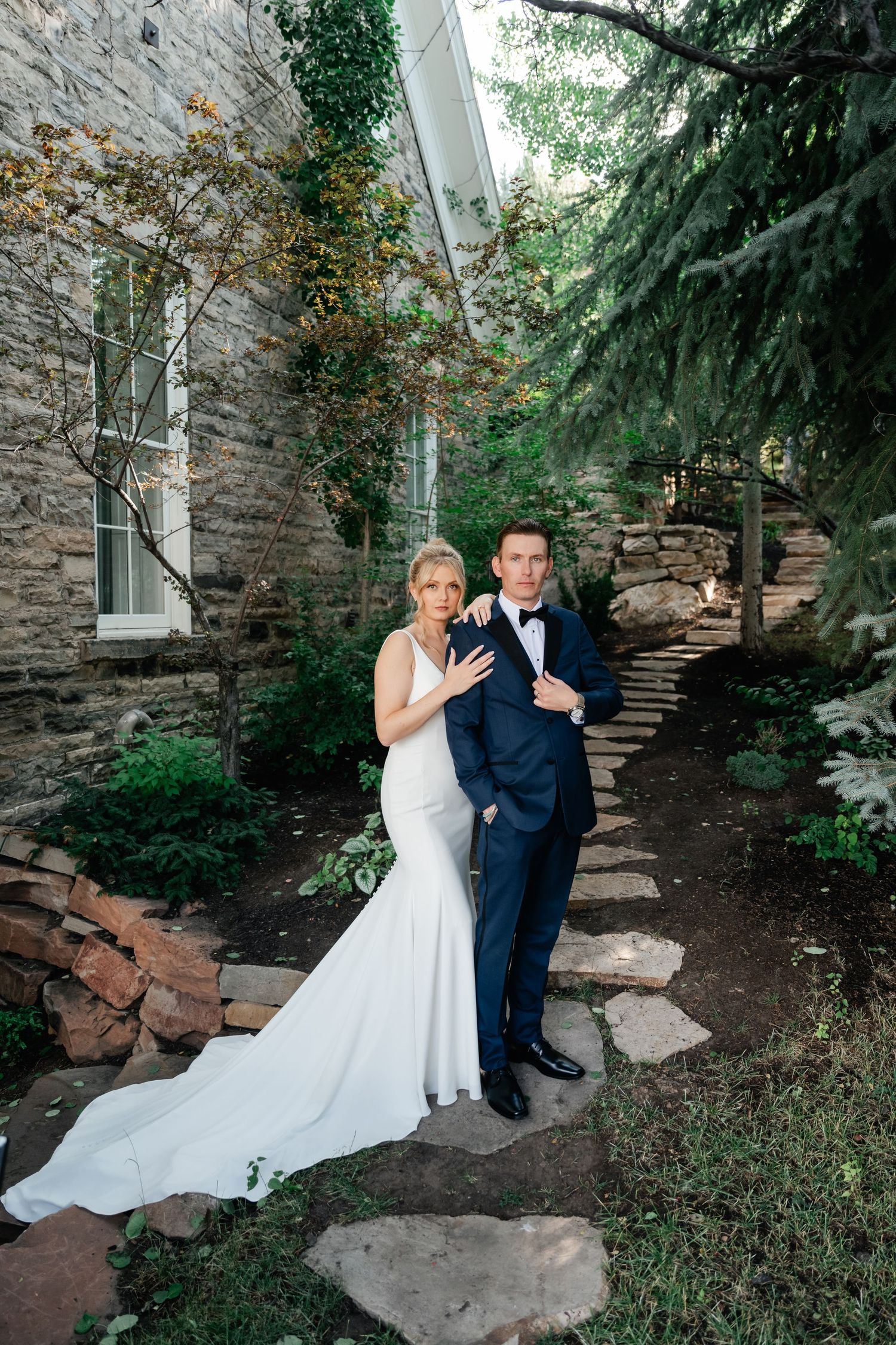 A romantic wedding scene in a stone garden courtyard with lush greenery and natural stone steps.