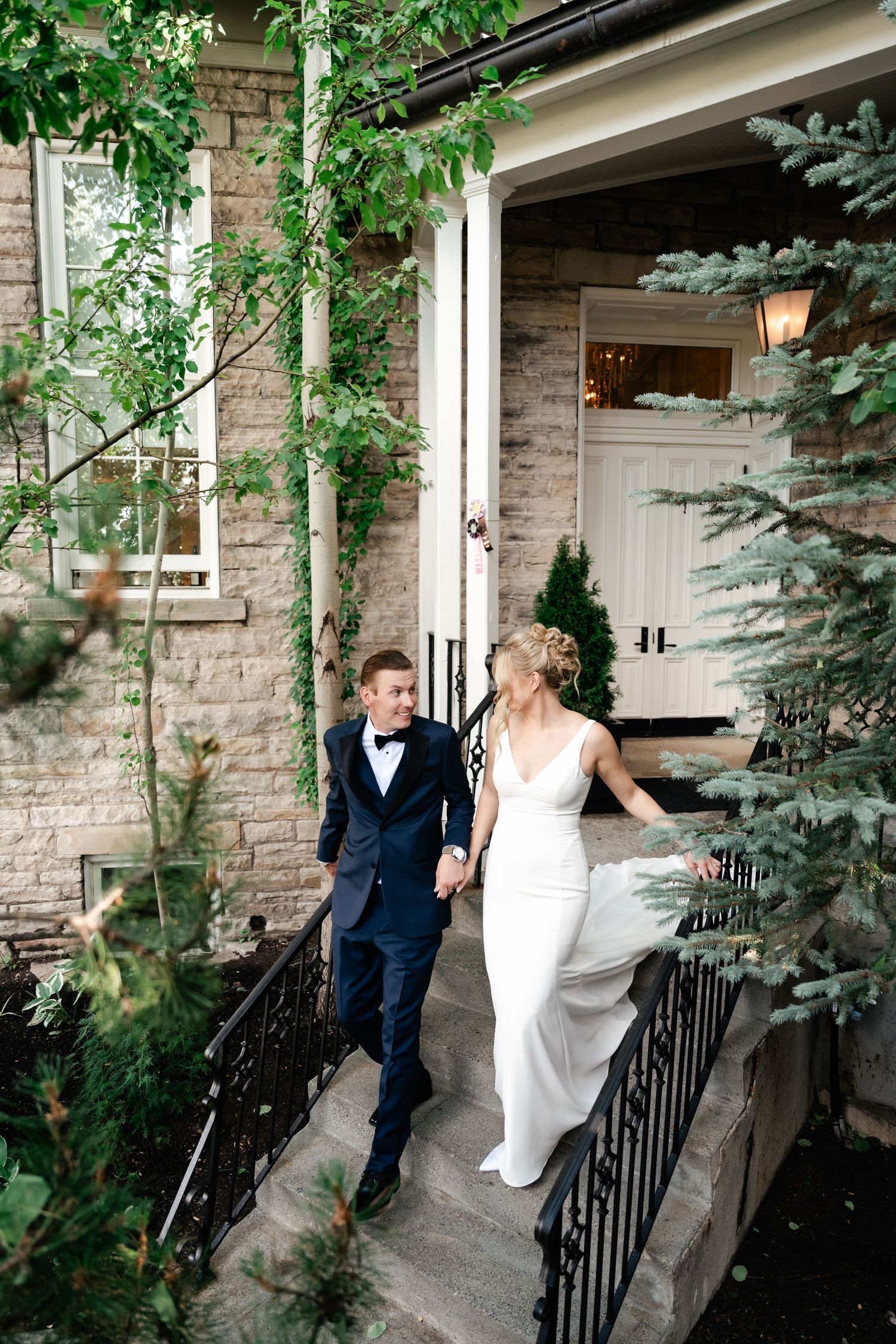 Wedding couple dancing and twirling on an outdoor porch surrounded by greenery.
