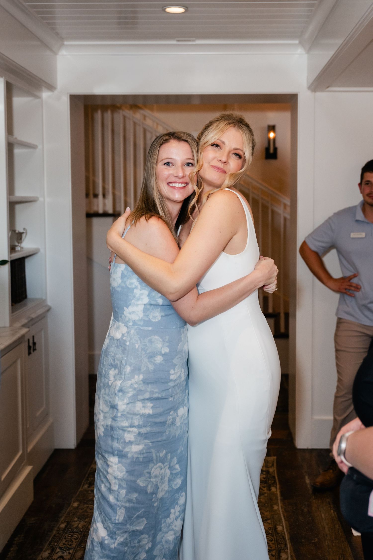 Wedding celebration moment captured in bright interior hallway with hardwood floors.