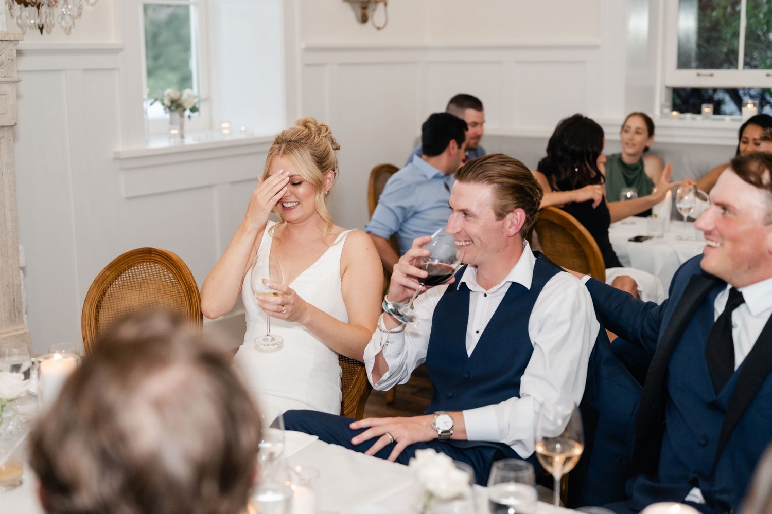 Wedding reception guests enjoy dinner and conversation at elegant indoor venue.