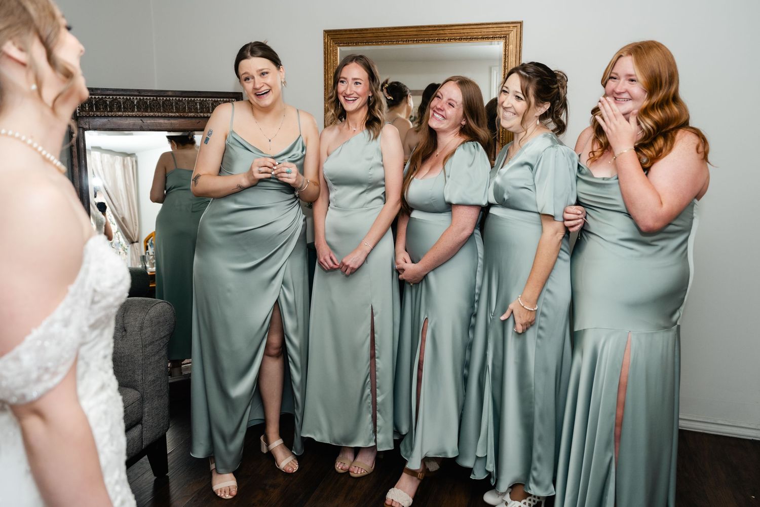 A group of bridesmaids in sage green dresses laugh together during a wedding celebration. Park City Wedding Photographer.