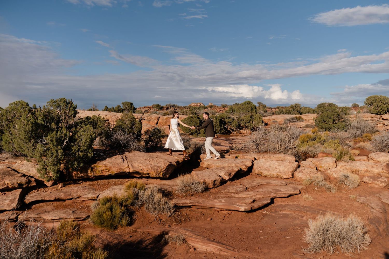 Panoramic view of red rock formations and desert landscape under blue skies.