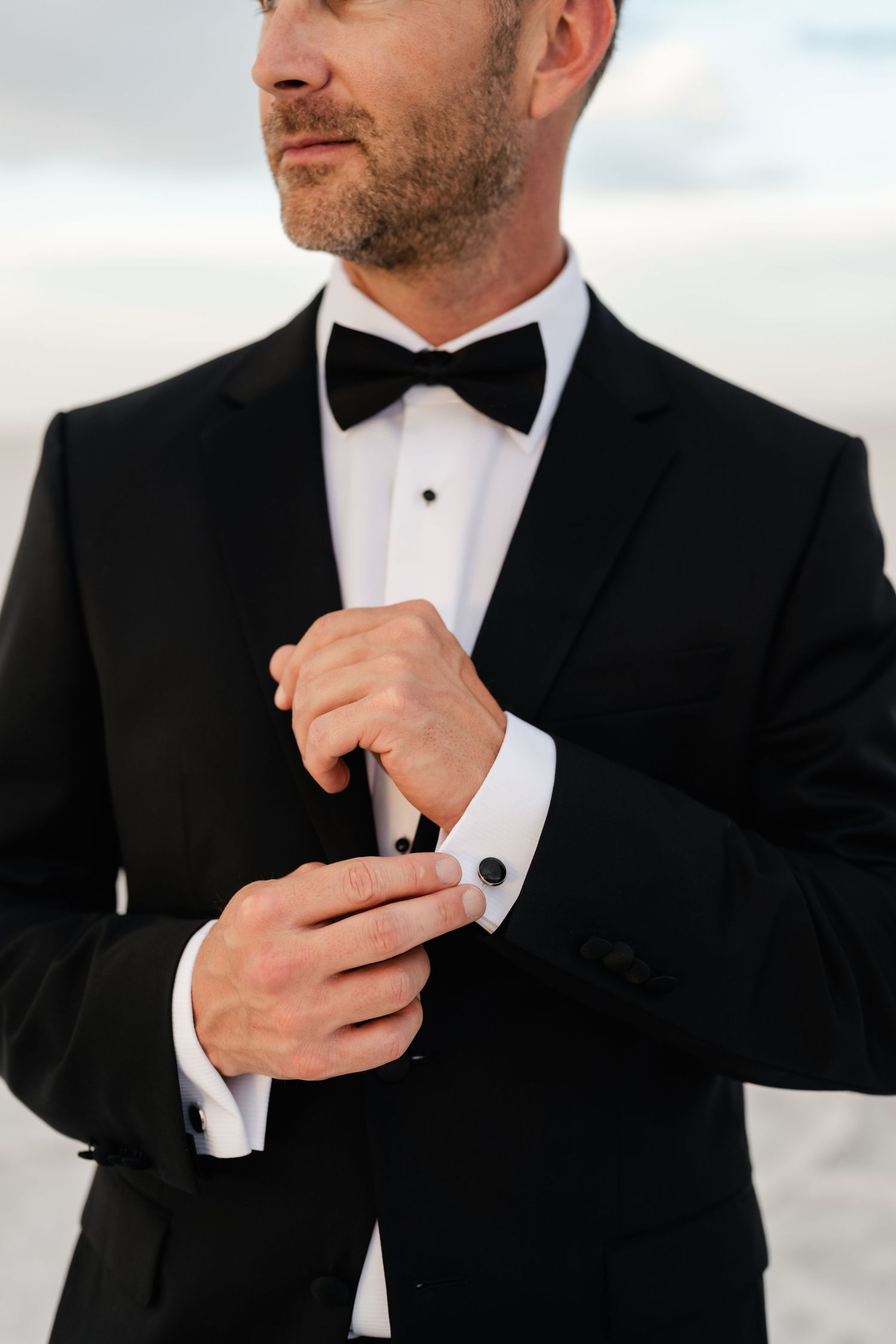 Salt Flats Elopement Photographer. Close-up details of a groom adjusting his tuxedo cufflinks and bowtie.