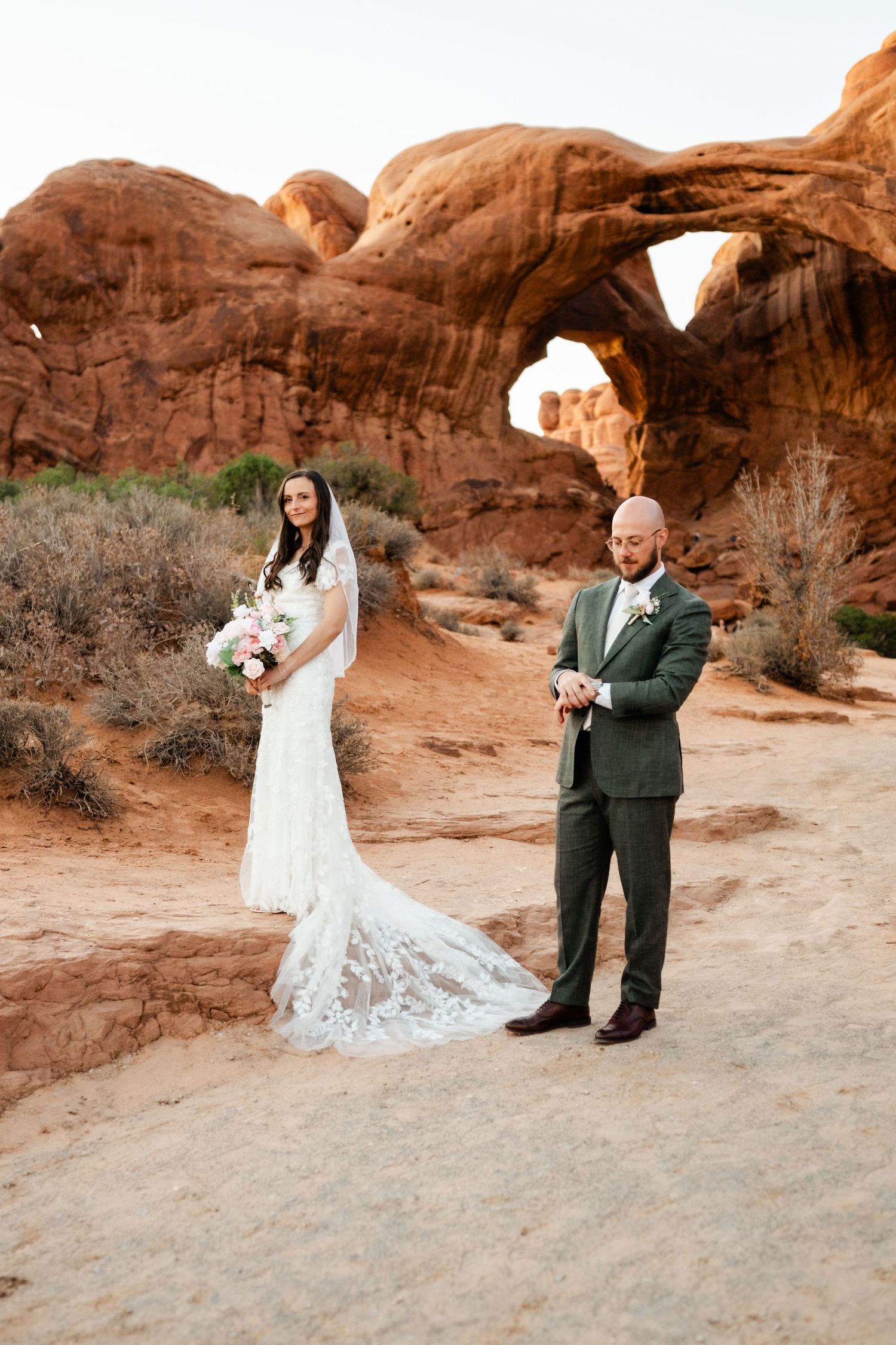 Wedding couple posing among stunning red rock formations in a desert landscape.