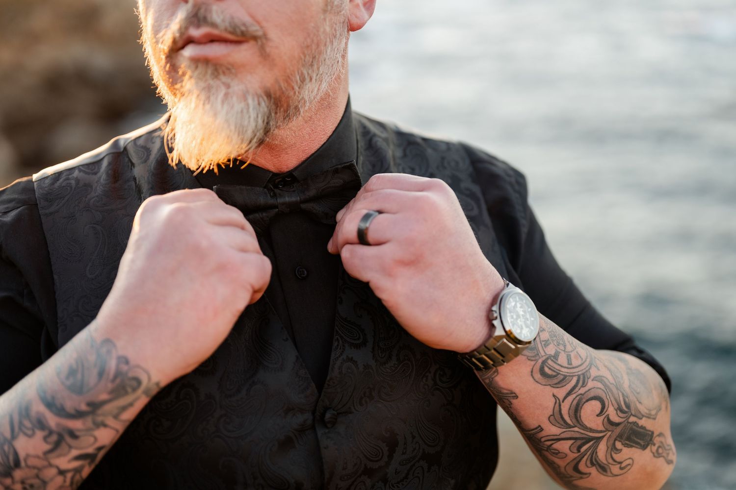 Close-up shots showing detailed tattoo work on formal wedding attire against an ocean backdrop.