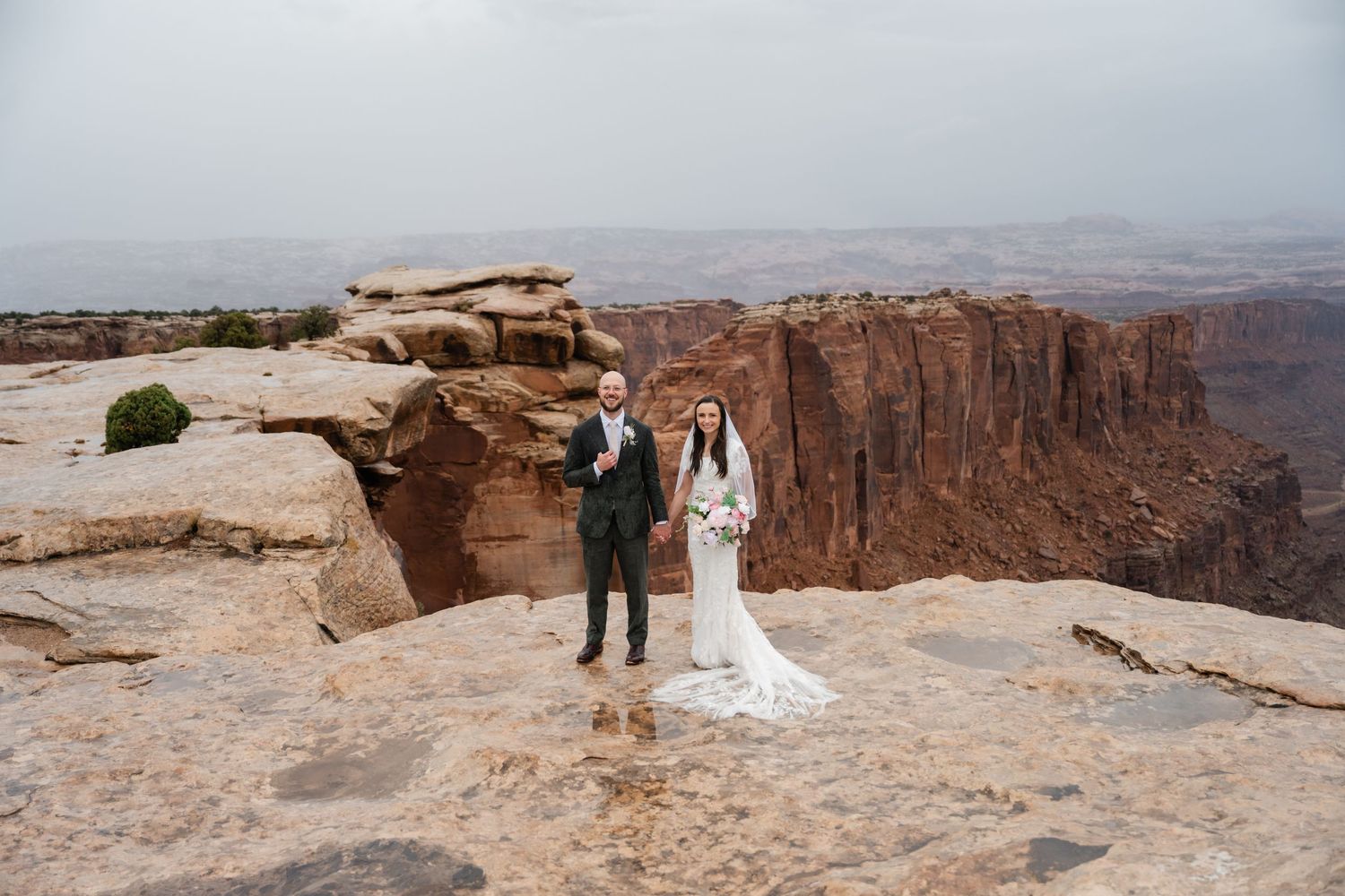 A panoramic view of a wedding ceremony location on a desert cliff with vast canyon vistas.