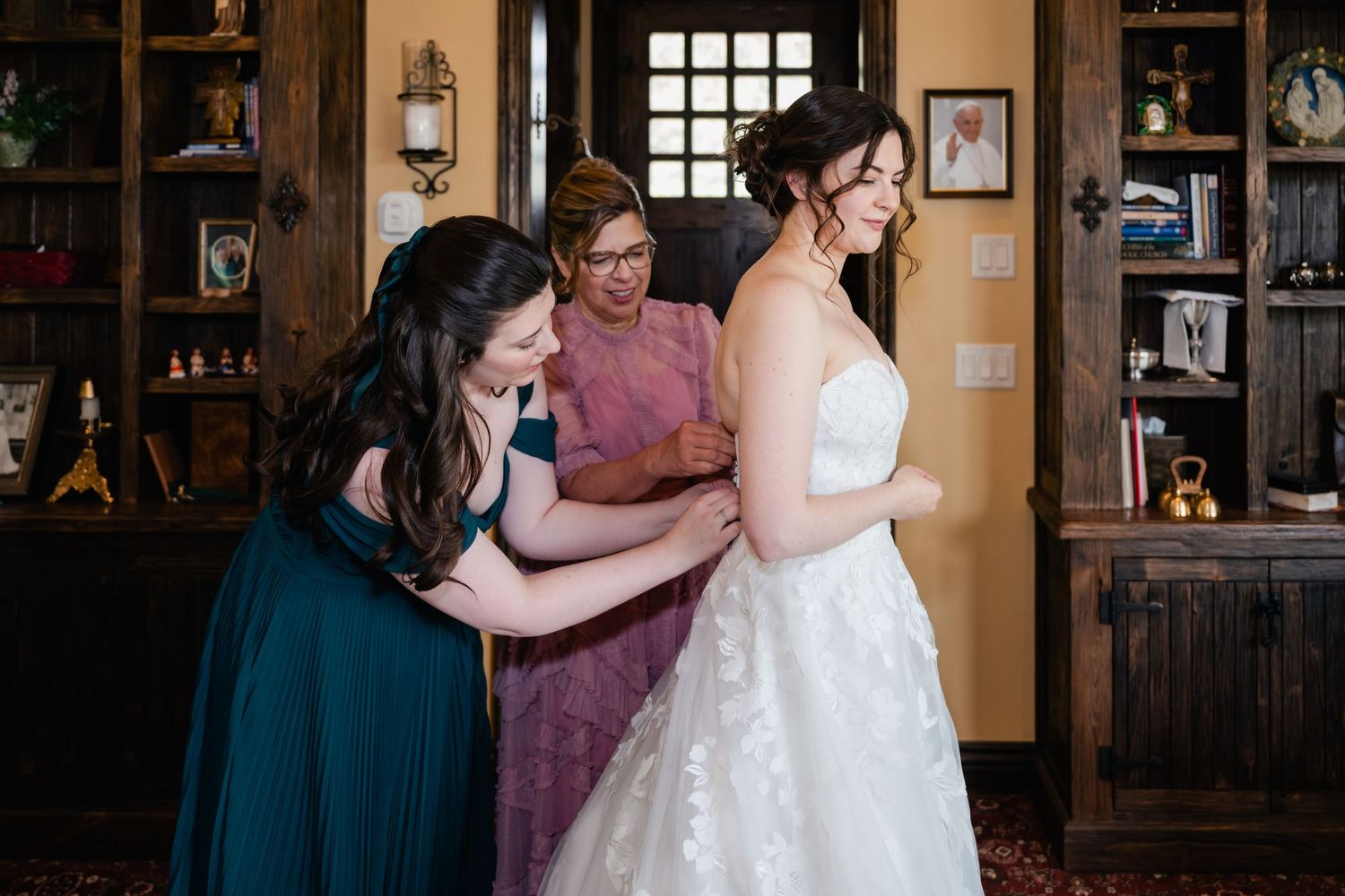 Wedding dress fitting scene in an elegant wood-paneled room.